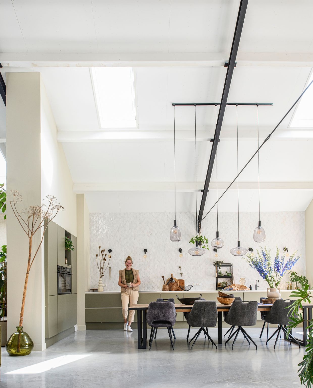 Muurverf Havermout van Gamma. Tegels Platta La Vie van Designtegels. Keuken Graafschap Keukens in de kleur ral 7002. Eettafel zelfgemaakt. Eetkamerstoelen Mx Sofa. Hanglampen Alton van Nordlux. Rek Goudmethout. Vloervaas en vaas op aanrecht Intratuin. Tak geplukt. vtwonen 03-2026 | styling Marit Saladini | fotografie Louis Lemaire