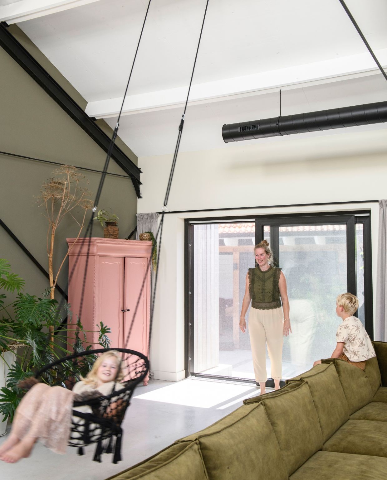 Muurverf ral 7002 en Havermout van Gamma. Vloer van woonbeton. Kast kleur Baked Clay van Gamma. Bank Alburg van Profijt Meubel. Hangende stoel Xenos. Tak geplukt. vtwonen 03-2026 | styling Marit Saladini | fotografie Louis Lemaire