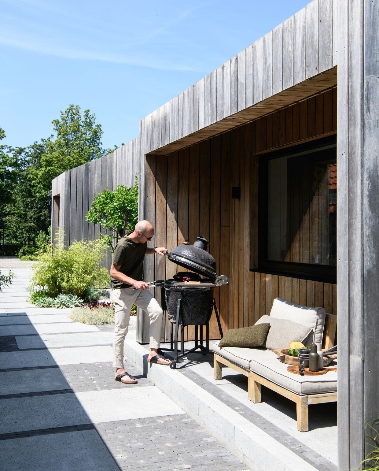 Barbecue Kamado Elite XL. Loungebank en kussens Intratuin. Serveerplank Loods 5. Serveerschaal uit Nepal. Peper-en-zoutstel Audo Copenhagen.