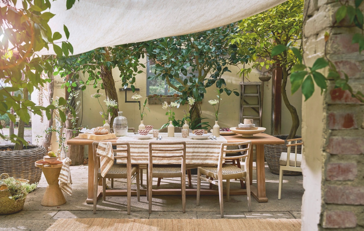 Gommaire eettafel Goss-Nac, teakhout, 250x100x76 cm (lxbxh) € 3224,-, eetkamerstoel Jared, teakhout en wicker, 46x47x78 cm (bxdxh) € 444,-, bijzettafel, hout € 217,80, pot rotan, bruin € 217,80, broodplank, hout € 43,56 (achterhuis.nl). Household Hardware borden Zigzag, keramiek, beige € 21,-, kom Zigzag, keramiek, beige € 12,50, bekers, keramiek, geruit wit en bruin € 12,50, schaal, tadelakt, wit € 121,-, schaal, hout € 21,- (householdhardware.nl). By Mölle bestek Brick Lane lepel € 7,-, vork € 7,-, mes € 12,- (bymolle.com). Zara Home tafelkleed, linnen, wit en bruin € 69,99, servetten, set van 2 € 15,99, dienblad, rotan € 49,99 (zarahome.com). Vazen oude kruiken en limonadekruik Marktplaats. Overig privébezit. vtwonen Landelijk 03-2026 | fotografie Jeroen van der Spek | styling Cleo Scheulderman