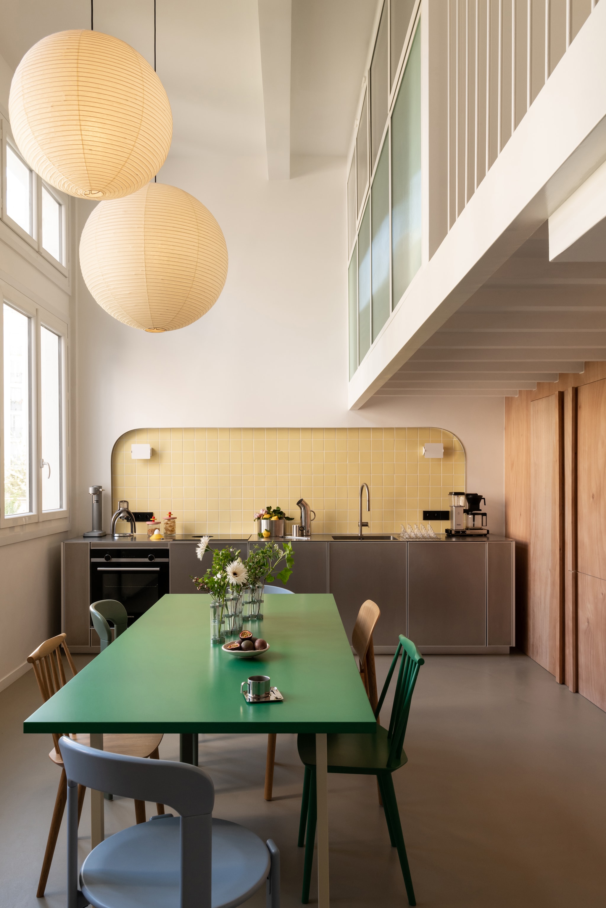 Tafel van Muller Van Severen voor Hay. Stoelen J77 en J104, Rey en Soft Edge van Hay. Hanglampen Akari van Isamu Noguchi voor Vitra. Kopjes met standaard Guido Bergna. Vaas Tsé & Tsé. Karaf Pipe van Normann Copenhagen. Tegels Faïence van Ce.si. Keuken Reflect door Jean Nouvel voor Reform Kitchen. Werkblad in roestvrij staal. Kraan Hansgrohe. Koffiezetapparaat Moccamaster. vtwonen Design 06-2026 | fotografie Agathe Tissier | productie Living Agency