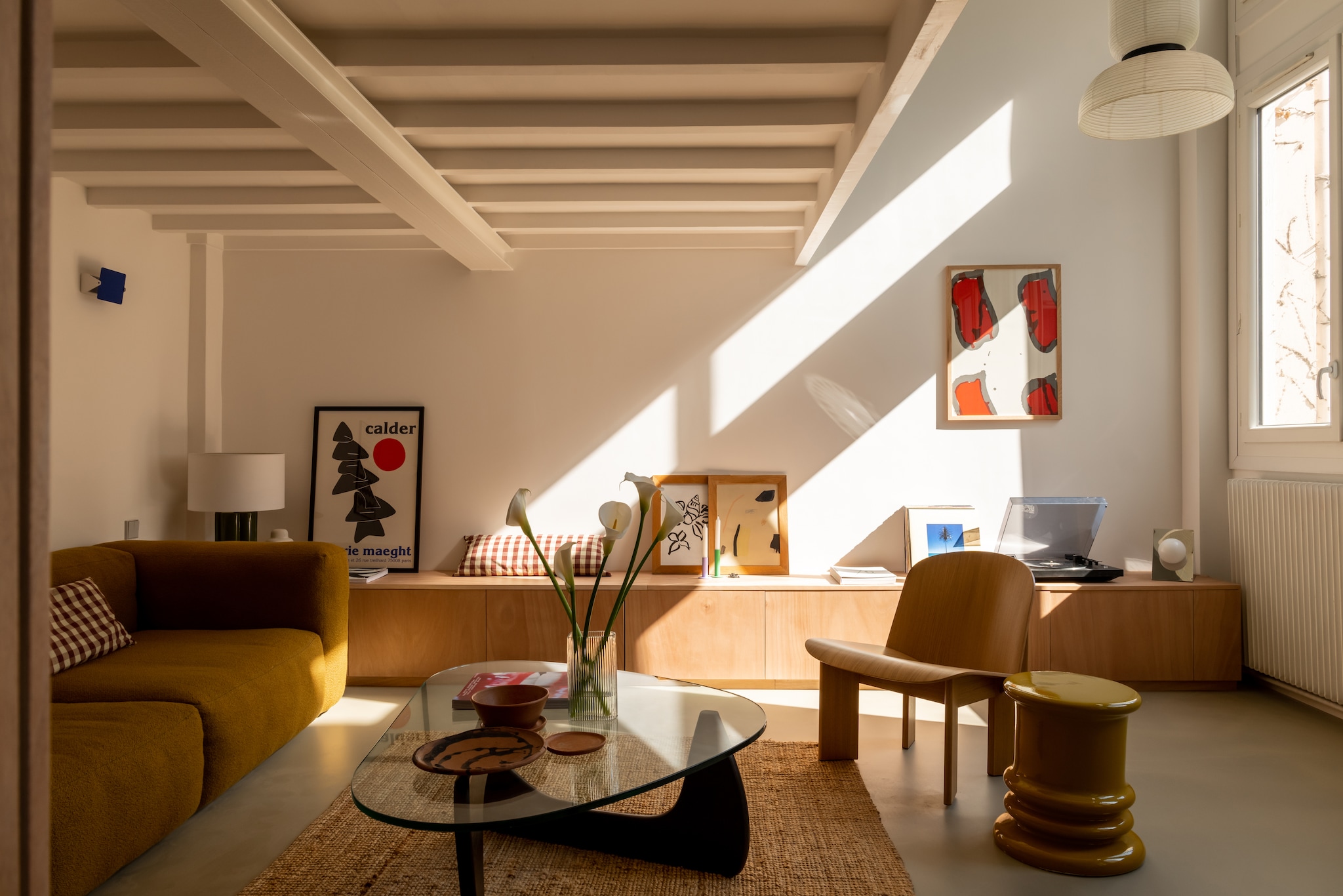 Vloer gegoten beton in kleur Borie van Mercadier. Hanglamp Formakami Jh5 &Tradition. Dressoir Ikea. Bank Mags Soft van Hay, bekleed met Flamiber Olive E9 stof. Fauteuil Chisel van Hay, ontworpen door Andreas Bergsaker. Salontafel in Noguchi-stijl. Posters galerie Maeght van Alexander Calder, Shell Flower van Hôtel Magique. Zeefdruk Claude Viallat. Kruk Jean-Pierre Garrault voor Monoprix. Tafellamp India Mahdavi voor Monoprix. Keramiek handgemaakt in Oaxaca, Mexico. Vaas Elements van Hübsch. Platenspeler Sony. vtwonen Design 06-2026 | fotografie Agathe Tissier | productie Living Agency