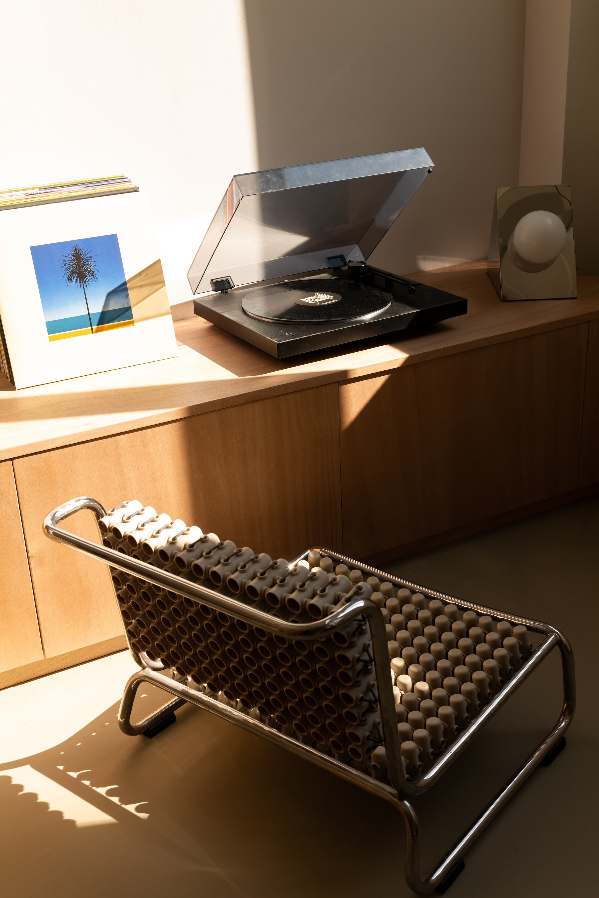 Bank met geïntegreerde opbergruimte op maat gemaakt in okoumé multiplex. Stoel Accupunto door Yos & Leonard Theosabrata. Platenspeler Sony. Tafellamp van Axel Chay voor Monoprix. vtwonen Design 06-2026 | fotografie Agathe Tissier | productie Living Agency