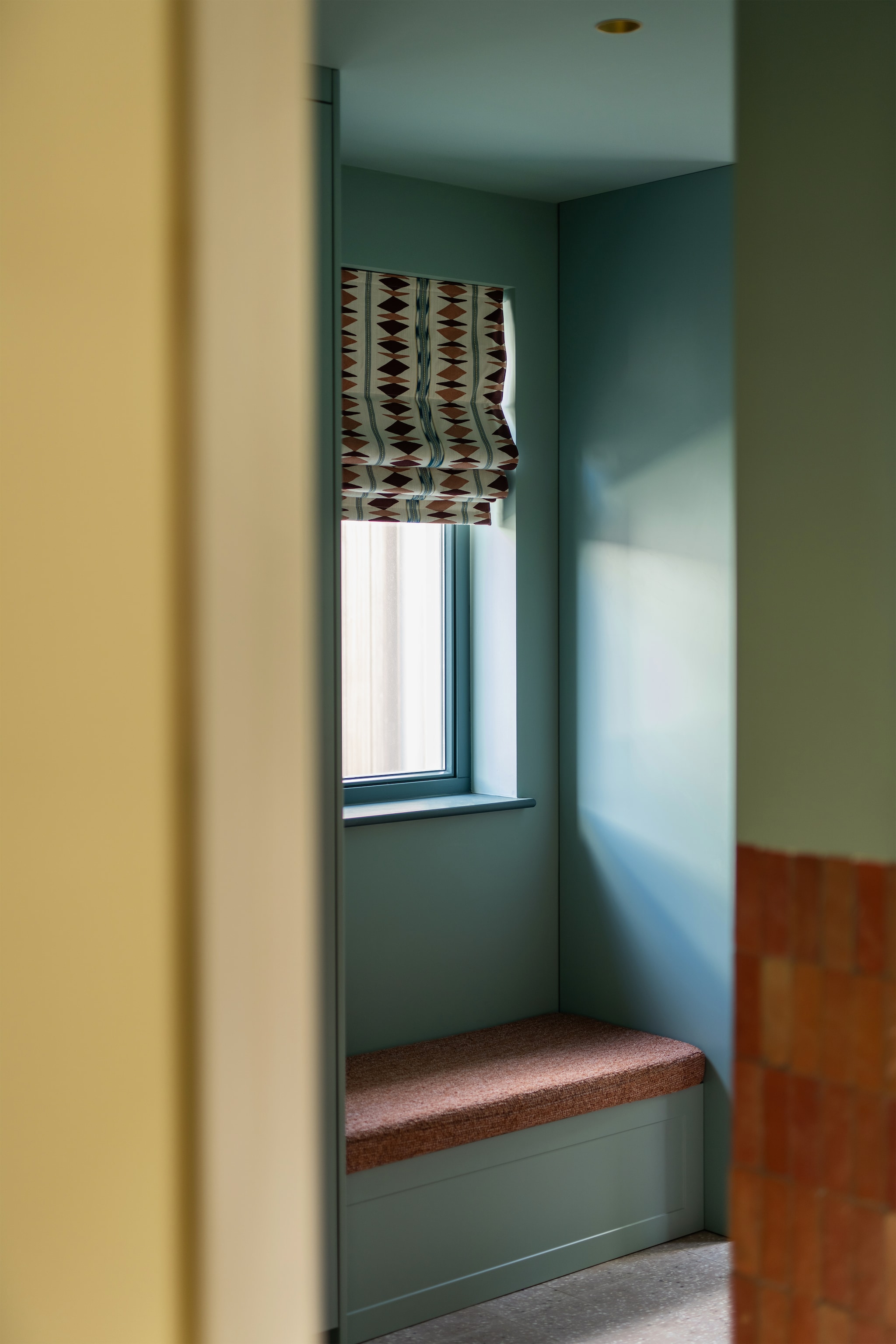 Verfkleur muren en kasten in de bijkeuken Dix Blue, kozijnen Inchra Blue van Farrow & Ball. Vouwgordijnen maatwerk met stof van Osborne & Little. Kasten en bankje maatwerk via K14, bekleed met stof van De Groot Stoffen. Tegels Designtegels. vtwonen Design 06-2026 | styling Juliette de Dreu | fotografie Lotte van Uittert