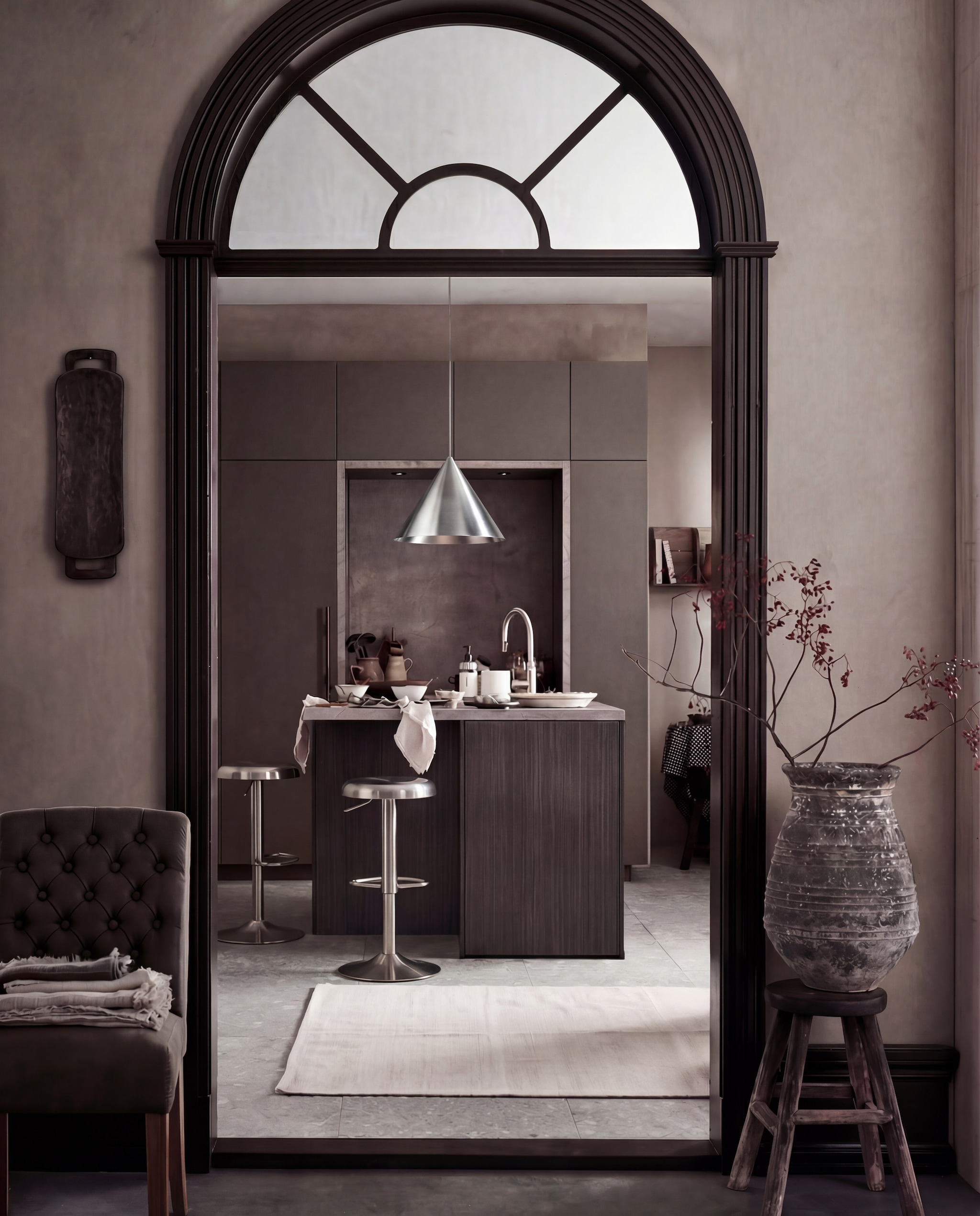 vtwonen keuken Tricole, agaatgrijs, in deze opstelling € 23.500,-. M.m.v. pure-original.com (muurverf Fresco kalkverf sand storm, lakverf Traditional Paint Eggshell fondant), vtwonen.nl (vloertegel Composite dark grey van vtwonen), hetkabinet.nl (eetkamerstoel Lara, oude onbehandelde kruk), zarahome.com (houten dienblad aan de wand, vloerkleed, linnen geruit tafelkleed, servet), loods5.nl (oude vaas), kare.nl (barkrukken), frandsen.com (hanglamp Benjamin). Overig privébezit.