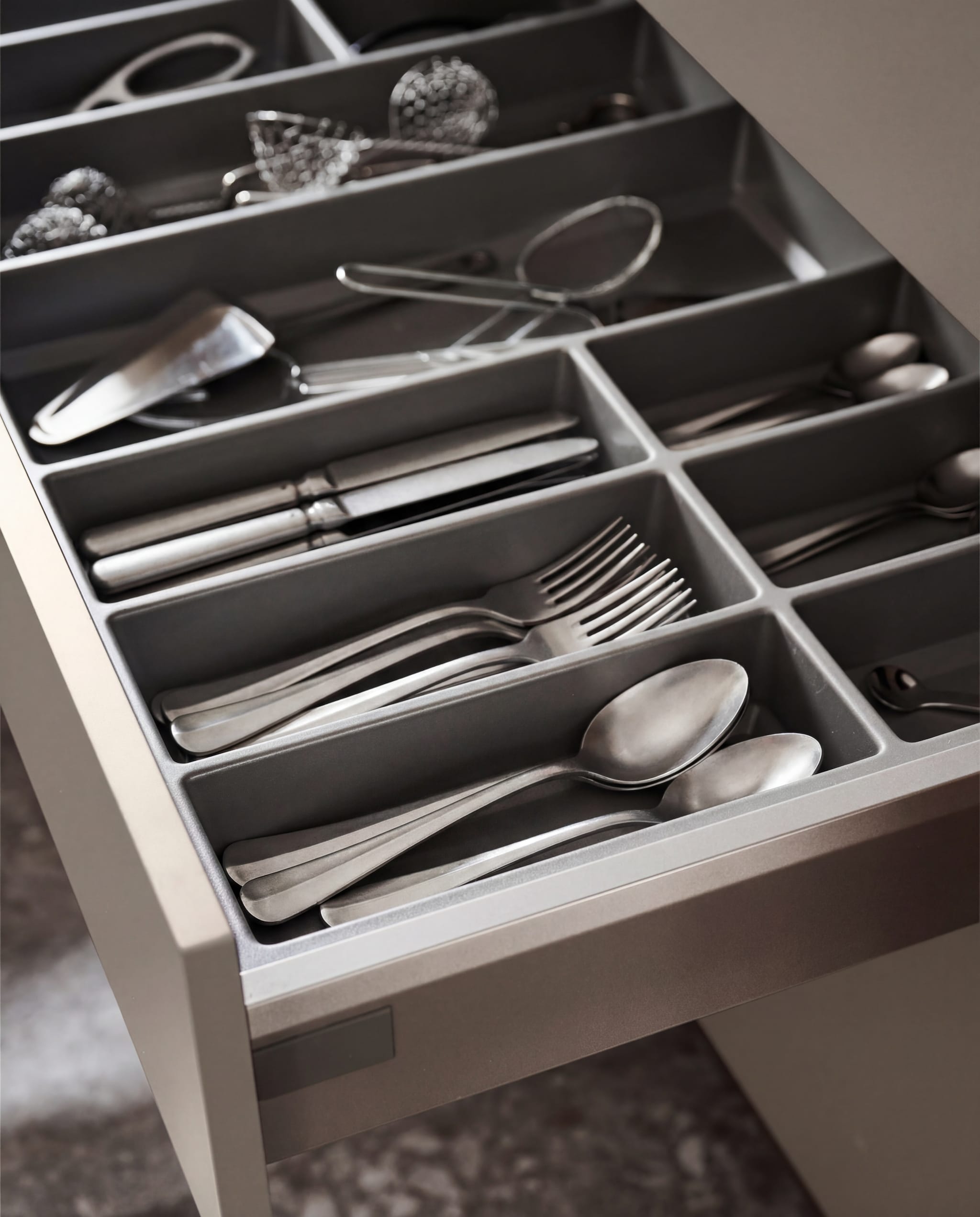 vtwonen keuken Tricole, agaatgrijs, in deze opstelling € 23.500,-.M.m.v. serax.com (bestek Surface van Sergio Herman). vtwonen.nl (vloertegel Composite dark grey van vtwonen), zarahome.com (kandelaars op pootjes), instagram.com/mettesophie.interiordesign (zwart kommetje, beker), housedoctor.com (handzeep, handlotionen ovale marmeren tray van Meraki), hetkabinet.nl (oude stenen terracottakleurige schaal). Overig privébezit. vtwonen 05-2026 | styling Kim van Rossenberg | fotografie Sjoerd Eickmans