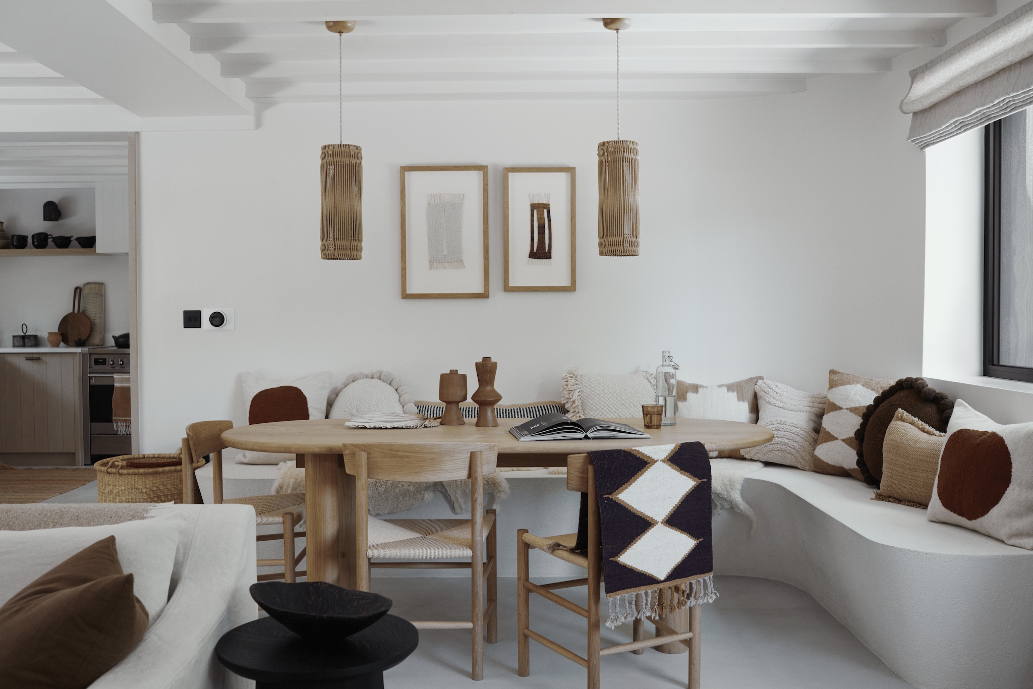 Bank op maat gemaakt door lokale timmerman. Kussens Pampa en By Mölle. Tafel Galvin Brothers. Stoelen Garden Trading. Ingelijste geweven werken Poppy Kural. Hanglampen Charlotte Packe Studio. vtwonen Landelijk 05-2026 | fotografie Brent Darby | productie Living Inside