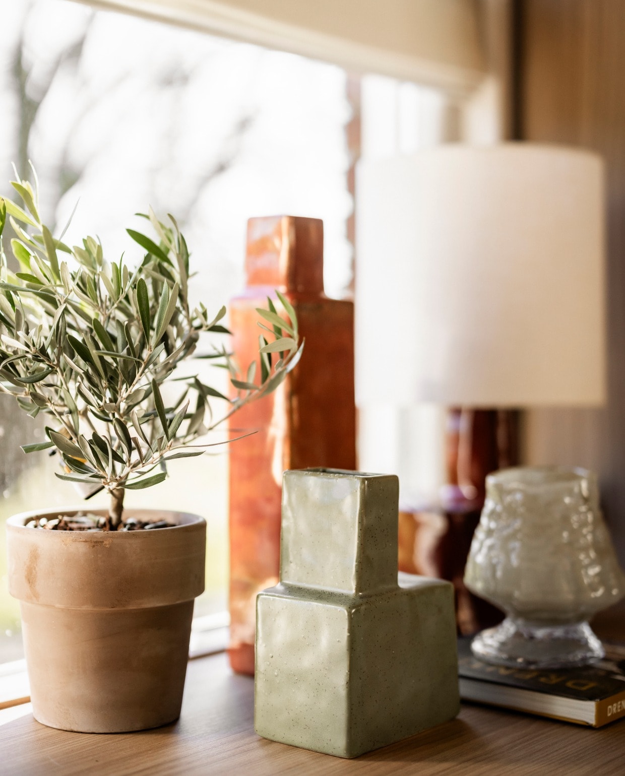 Vouwgordijnen Luxaflex Loft79 Casio Aanhuis. Vaas Koa in donkergroen en donkerrood, kaarsenset Dryp in donkerbruin Ferm Living. Vaas Morag Bloomingville.