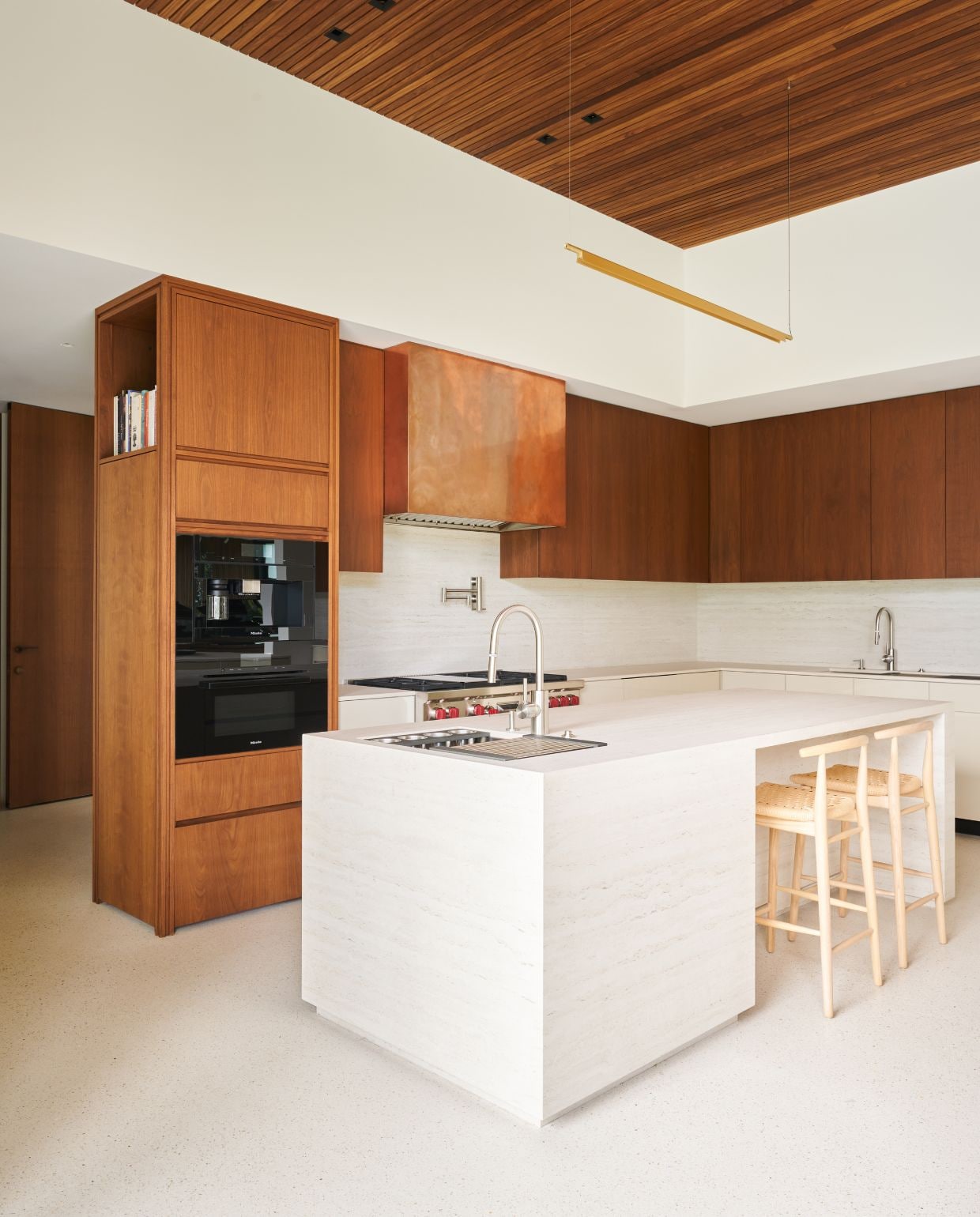 Op maat gemaakte walnoothouten keuken met travertijn eiland. Krukken Antonio Citterio voor B&b Italia. Hanglamp Luceplan. vtwonen Design 03-2026 | fotografie Valentina Sommariva