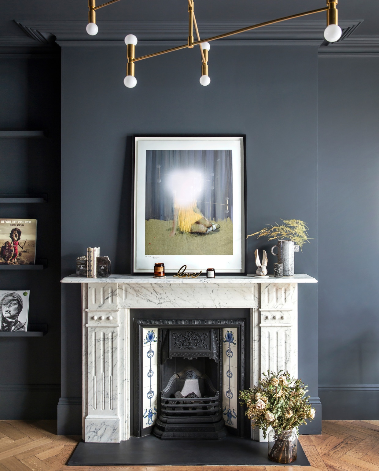 De woonkamer is de enige ruimte in donkere kleuren. Het kunstwerk van Charming Baker op de klassieke open haard geeft een surrealistisch effect.  De geometrische verlichting is van Lambert & Fils. vtwonen 01-2020 | fotografie Rei Moon / Living Inside