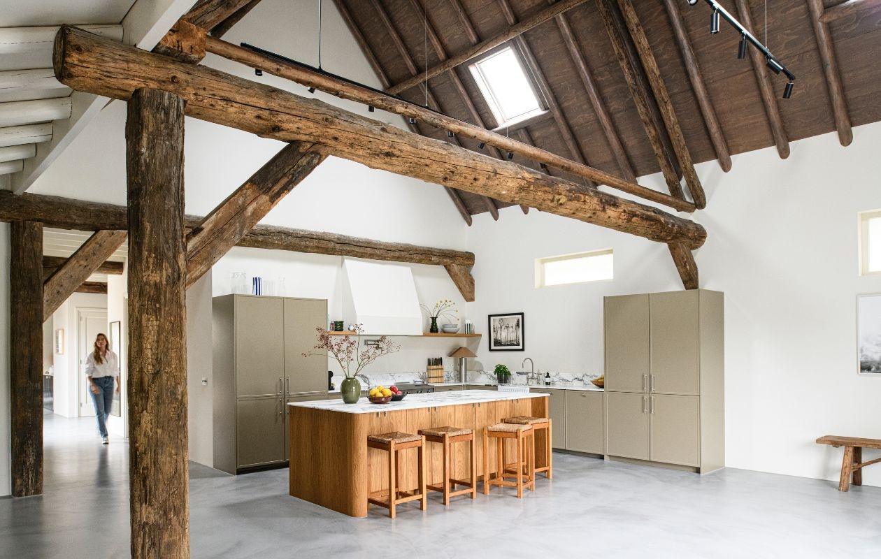Keukenkasten en eiland op maat gemaakt. Werkblad Arabescato marmer van Stone Creation. Spoelbak Devol Kitchens. Kraan, pot filler Studio Ore. Fornuis Bertazzoni. Greepjes Meraki. Vaas op werkblad Arket. Stalen lamp Zara Home. Krukken vintage. Muurverf School House White van Farrow & Ball.