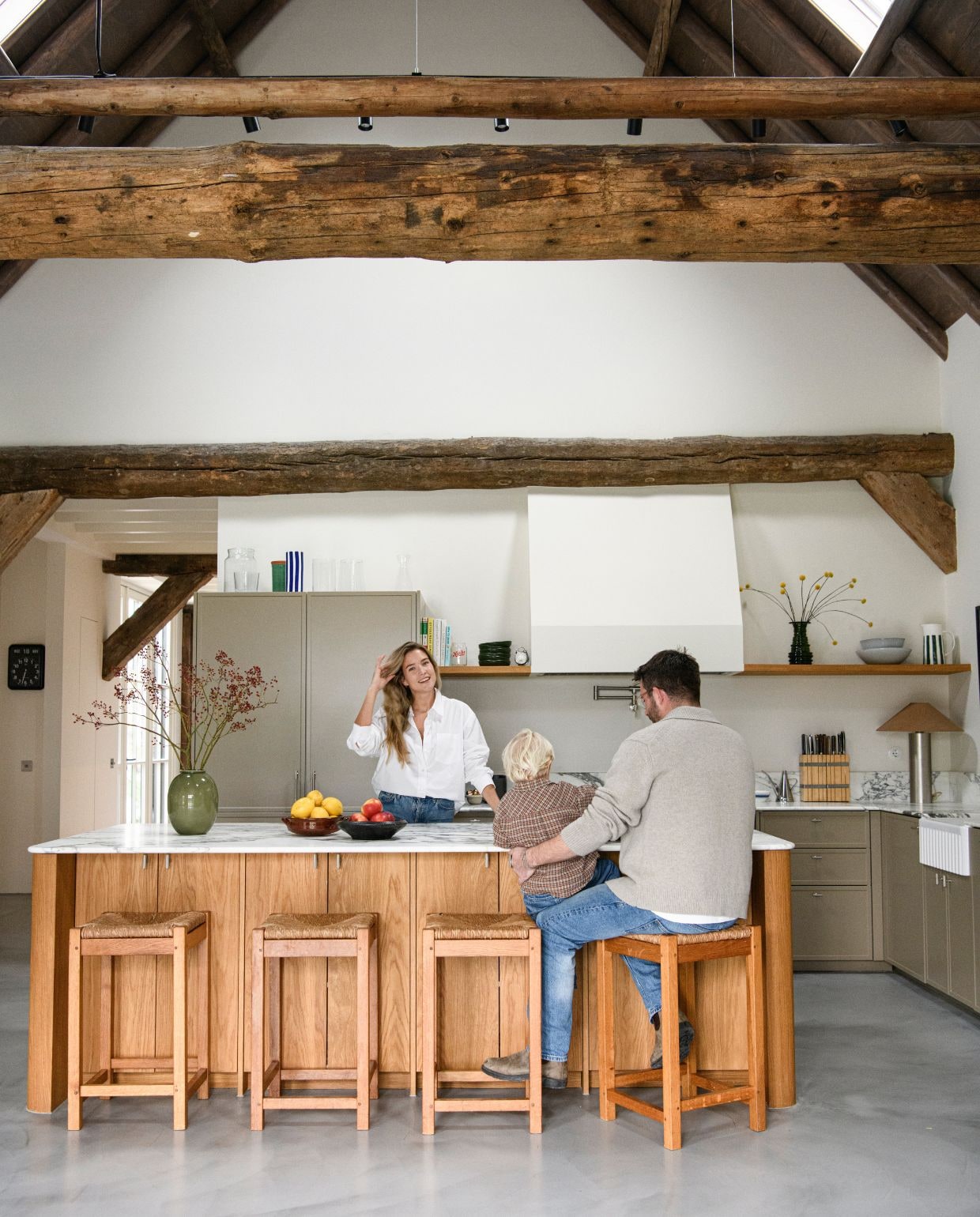 Keukenkasten en eiland op maat gemaakt. Werkblad Arabescato marmer van Stone Creation. Spoelbak Devol Kitchens. Kraan, pot filler Studio Ore. Fornuis Bertazzoni. Greepjes Meraki. Vaas op werkblad Arket. Stalen lamp Zara Home. Krukken vintage. Muurverf School House White van Farrow & Ball.