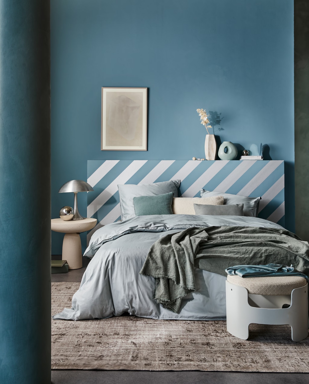 vtwonen collectie behangstrook Silver, 10,66 cm (b), rol van 10 m € 12,99. M.m.v. suite702.nl (satijnen beddengoed in Glacier Grey), neeflouis.nl (poef), edha-interieur.nl (bijzettafel), pietjonker.nl (zilveren lamp), urbannatureculture.com (vazen), rozenkelim.nl (vloerkleed), theposterclub.com (ingelijste poster), zarahome.com (linnen plaid, kussens), vtwonen.nl (muurverf in Old Blue). Overig privébezit. productie Tanja Saarberg | styling Cleo Scheulderman | fotografie Jeroen van der Spek | assistentie Kelly van Gendt | studio en decorbouw Studio Milo