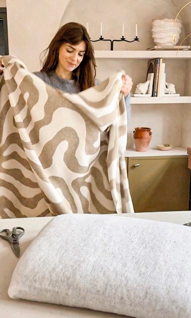 Plaid Libbe van Dutch Decor via shop.vtwonen.nl. Kunstwerk Studio Vreeken. Vloerkleed Lorena Canals. Zitkussen zelfgemaakt. Fauteuil en rolkussen tweedehands. vtwonen 04-2026 | fotografie Valerie Paas