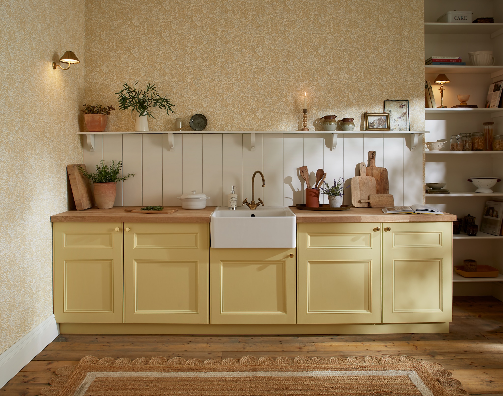Graham & Brown keukenfronten geschilderd in kleur crème brûlée en wand in kleur ginger lily, Ultra Matt Resistant Emulsion, 2,5 liter € 120,-, behang Daisyfield, crème brûlée, 52 cm x 10 m (bxh), per rol € 125,- (grahambrown.com). vtwonen Landelijk 06-2026 | Graham & Brown | fotografie Nicola Huthwaite