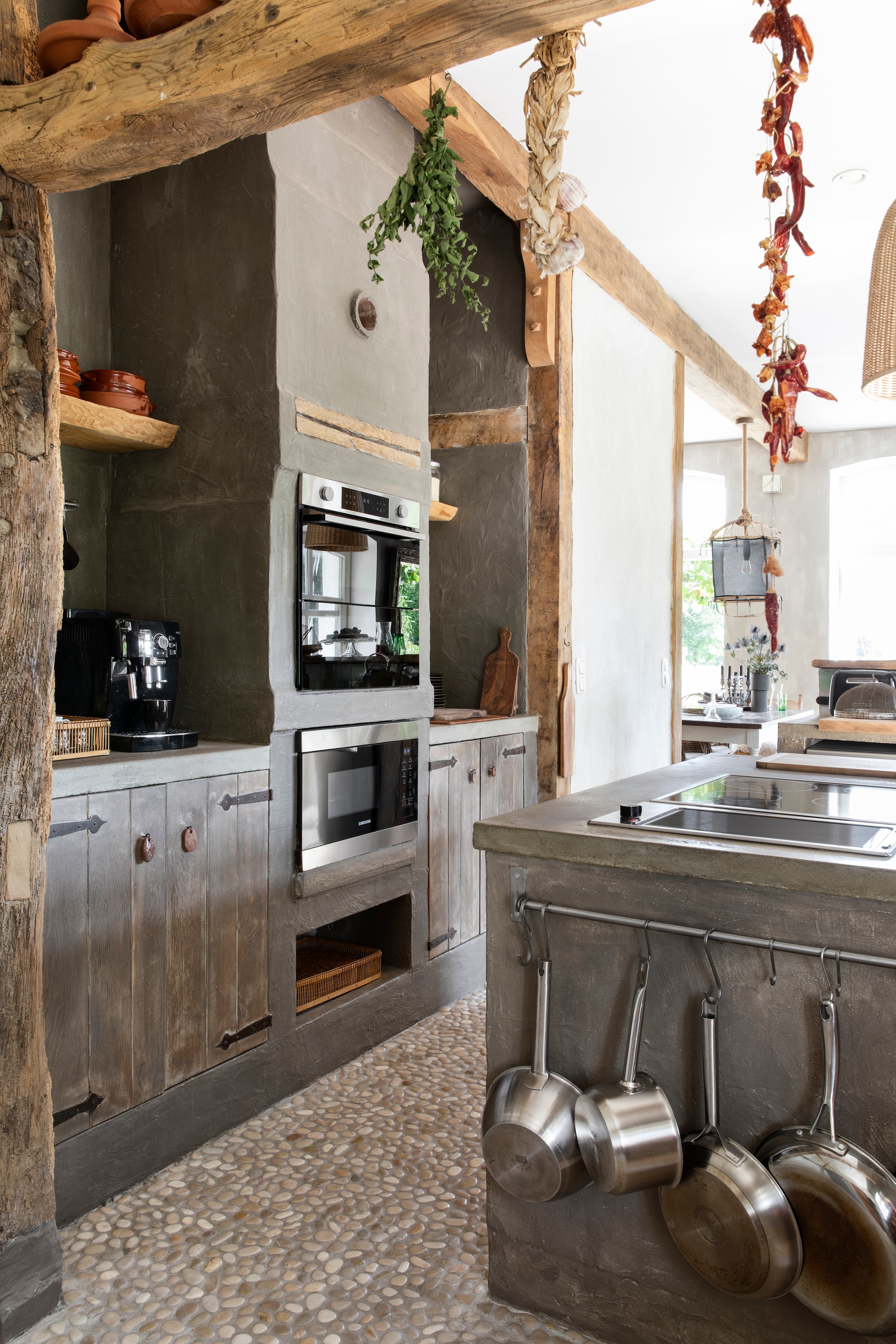 Keuken door Uschi ontworpen. Vloer Pebble Shop. De balkenconstructie van het huis is gezandstraald en in het zicht gelaten. vtwonen Landelijk 07-2026 | styling Miriam Hannemann | fotografie André Reuter