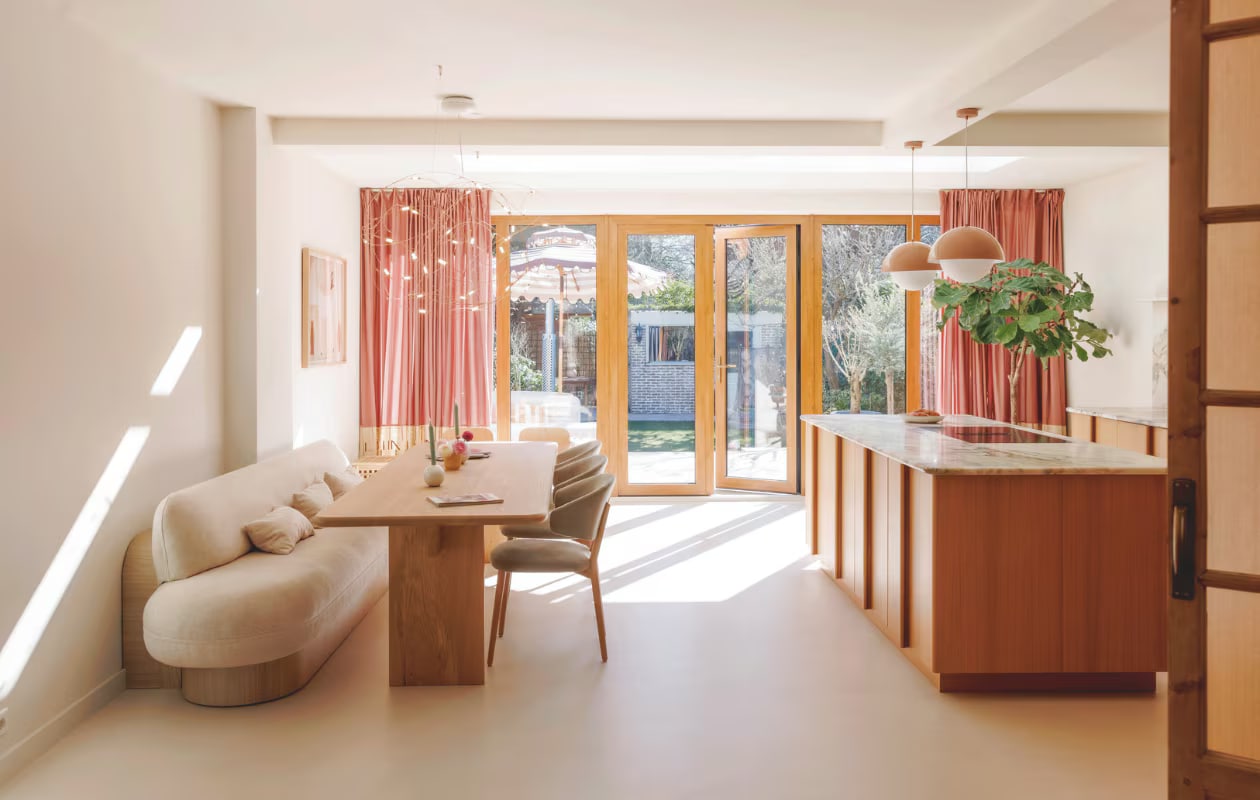 Stoelen in stof Guard Eucalyptus 193 en tafel Table du Sud. Bank, kussens Studio Diezijn. Kandelaars Leen Bakker. Hanglampen en vaasje Westwing. Maatwerkkeuken Reform. Keukenblad Jan Reek natuursteen. Gordijnen zelfgemaakt. Stone Age vloer Beton Ciré crème- grit. Muurverf Overtoom uit Interieurvanmies-kleurencollectie van Fairf. Schuifpui eigen ontwerp. vtwonen 7-2025 | fotografie Emma Peijnenburg