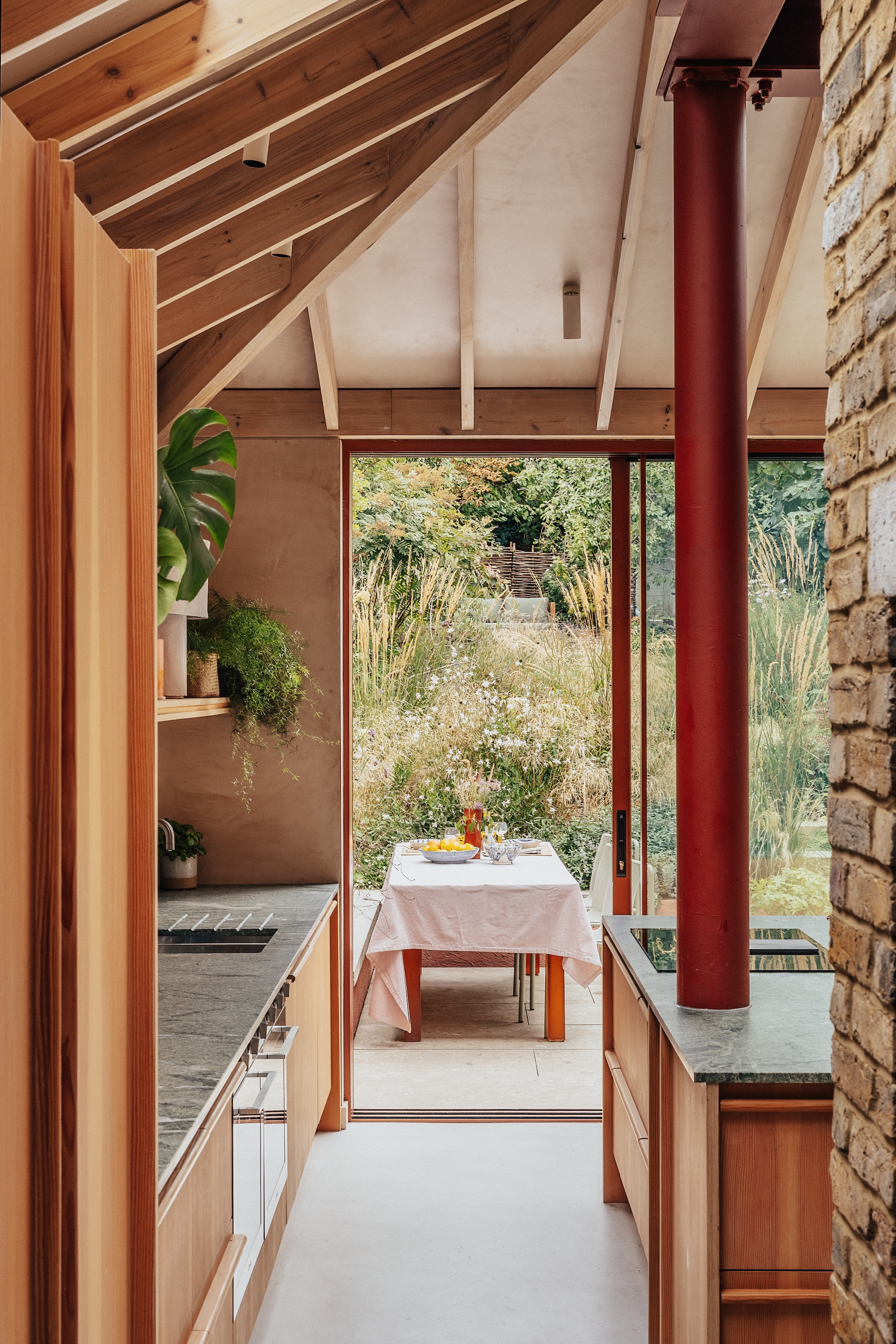 Keukenontwerp Bechtolsheim Studio, uitgevoerd in berken multiplex en afgewerkt met Douglas-fineer. Fruitschaal Caroline Owen. Buitentegels Cosmo Sand van Sant’Agostino. Rode vaas Sola van Ferm Living. vtwonen 07-2026 | fotografie Taran Wilkhu | productie Living Inside