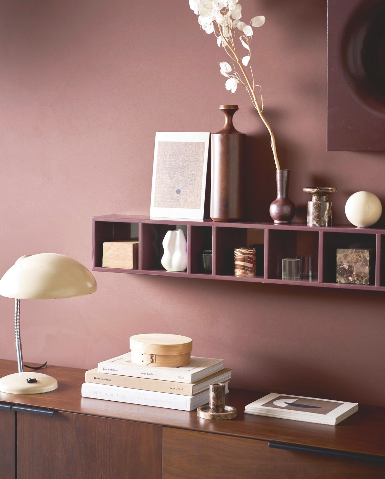 vtwonen wandkast Show it, mdf met hoogglans, burgundy red, 130x16x12 cm (lxbxd) € 89,95 (shop.vtwonen.nl).M.m.v. andtradition.com (fauteuil en poef Little Petra), edithbeurskens.com (wandobject en aardewerk bal), zuiver.com (dressoir), shop.vtwonen.nl (marmeren kandelaar van vtwonen), burbriantiek.nl (leeslamp), zarahome.com (marmeren kubus). Overig privébezit. vtwonen 04-2026 | styling Cleo Scheulderman | fotografie Jeroen van der Spek