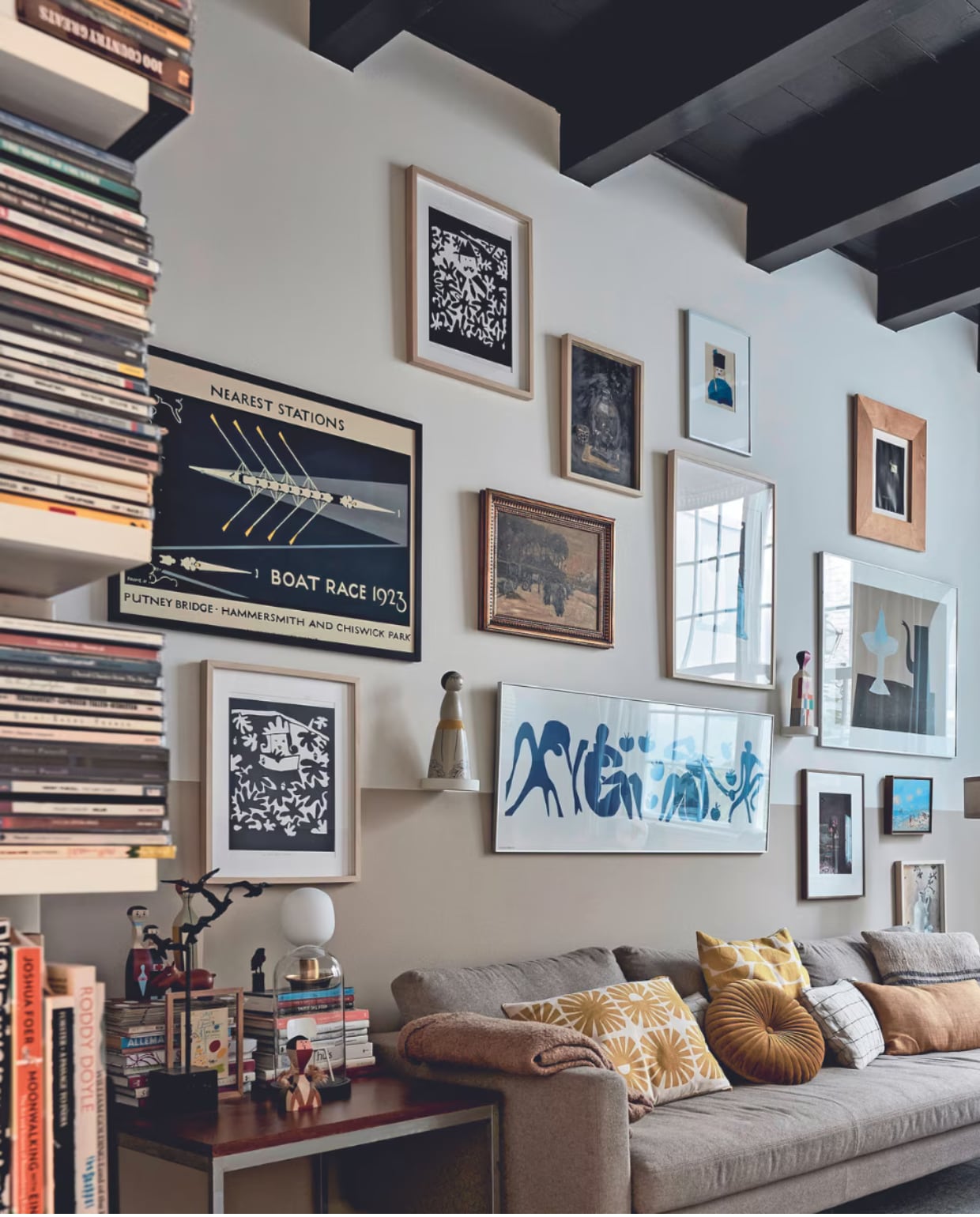 Bank Loods 5. Plaid, rond kussen en effen geel kussen Zara Home. Kussen met zonnetjes, geel-wit kussen, klein kunstwerk op bijzettafel cadeaus. Geblokt kussen zelfgemaakt van Habitat-stof, grijs kussen gemaakt met stof van de markt. Bijzettafel kringloop. Zwart kunstwerk vogels en kleine zwarte vogel familiestukken. Houten beeldjes en leren nijlpaard Vitra. Stolp met model van Revolt-stoel vintage. Tafellamp, vloerkleed en kap stalamp Ikea. Aan de muur: zwart-witte zeefdrukken, schilderij stilleven, persoon met zwarte hoed, groot rechthoekig wit werk in het midden en klein werk vaas met bloemen zelfgemaakt door Heleen. Boat Race 1923 en klein lichtblauw kunstwerk cadeaus. Zeefdruk theepot Klaas Gubbels, ingelijste poster Matisse Ikea, foto Frederique Masselink-van Rijn. Overige makers onbekend. Beeldje gekocht op Bali. Object Vitra. Muurverf Ral 9010 van Sikkens. Verf lambrisering Pure Mild Sand en plafond Royal Blue van Flexa. Overig onbekend. vtwonen 02-2024 | fotografie Alexander van Berge
