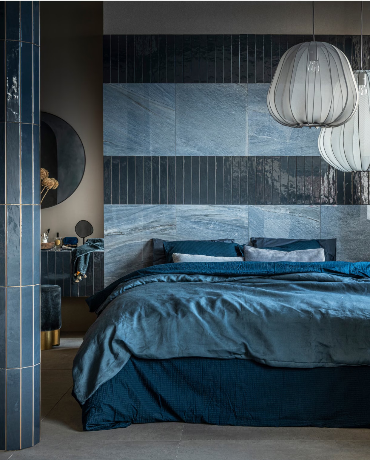 vtwonen collectie (Op de wand: vloer- en wandtegel Classic in kleur Heavenly Blue, glans, 60x60 cm, per m² € 77,95 (in mat € 71,90), wandtegel Marrakesh in kleur Ocean Blue, glans (ook in mat), 6,5x40 cm, per m² € 62,35. Op de vloer: vloertegel Raw in kleur Grey, 80x80 cm, per m² € 65,-). M.m.v. vtwonen.nl (stoffen hanglampen van Bolia), zarahome.com (ronde spiegel, staande spiegel, handdoek, donkerblauw beddengoed Minte van Essenza), ikea.nl (lichtblauw beddengoed Puderviva), melchiorinterieur.nl (poef, kussens), suhka.nl (houten schaal). vtwonen 11-2021 | productie Tanja Saarberg | styling Kim van Rossenberg | fotografie Sjoerd Eickmans