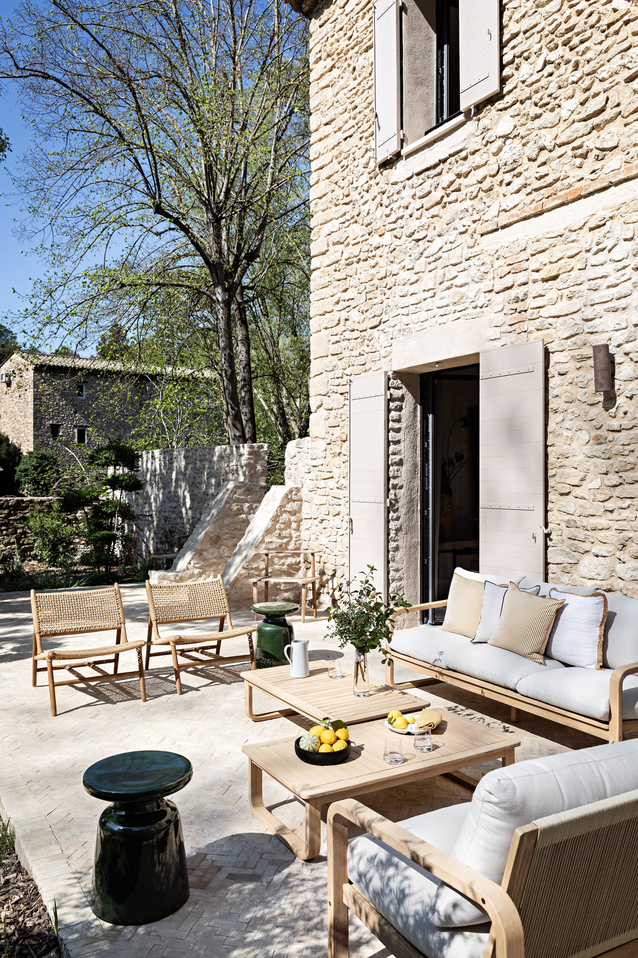 Terrasstoelen, banken en salontafels Sklum. Keramieken bijzettafels Kave Home. Zwarte schaal H&m Home. Gestreept kussen Maison de Vacances. Servies Ikea. vtwonen 08-2026 | styling Marie-Maud Levron | fotografie Yann Deret
