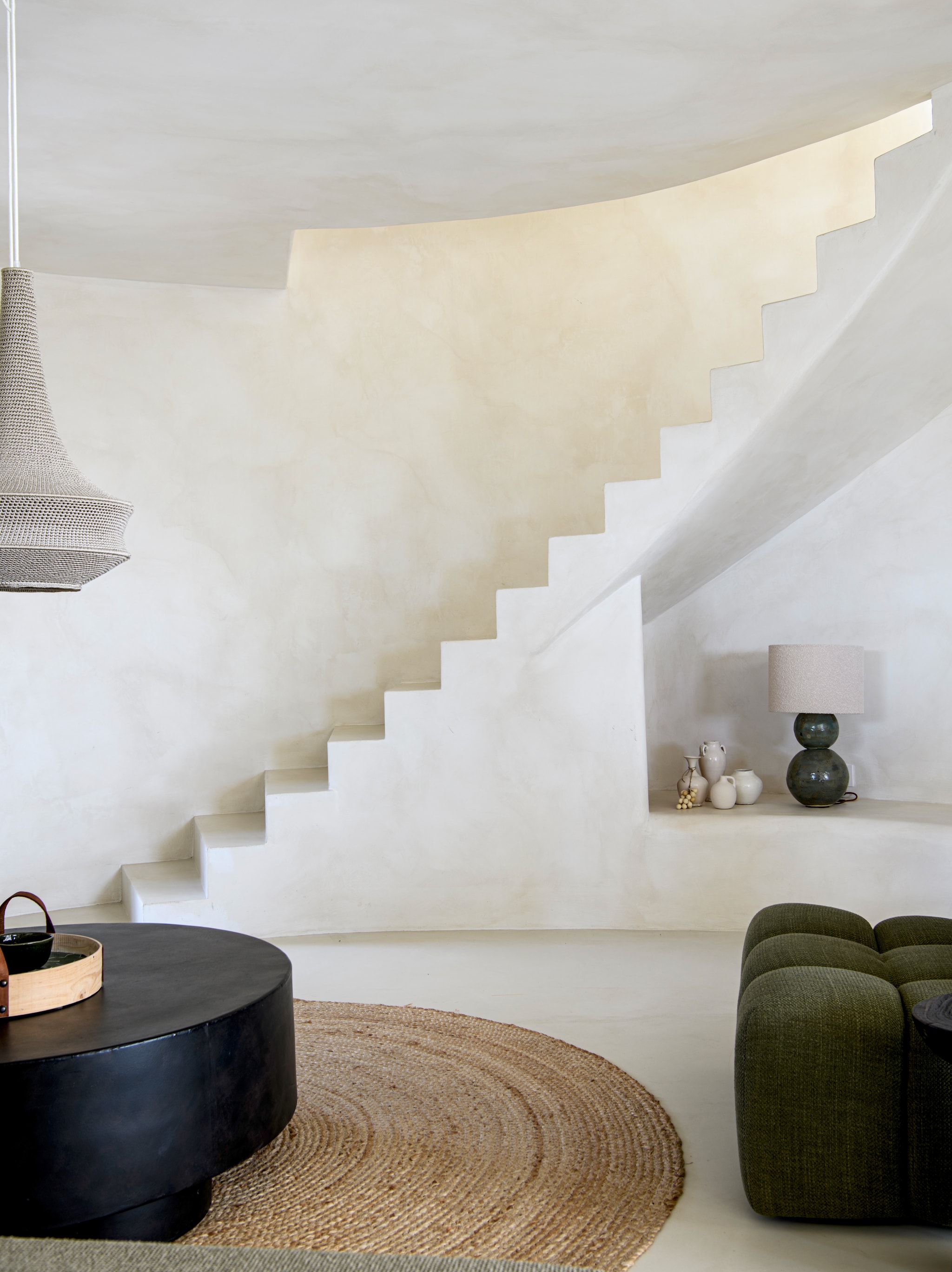 Microcementvloer Topciment. Muren geverfd met kalkverf Chalk van Bauwerk Colour. Koffietafel Tine K Home. Vloerkleed maatwerk. Hanglamp Hamimi Design. Fauteuil Dareels. vtwonen 08-2026 | styling Inge van Lieshout | fotografie Louis Lemaire | productie Insidehomepage