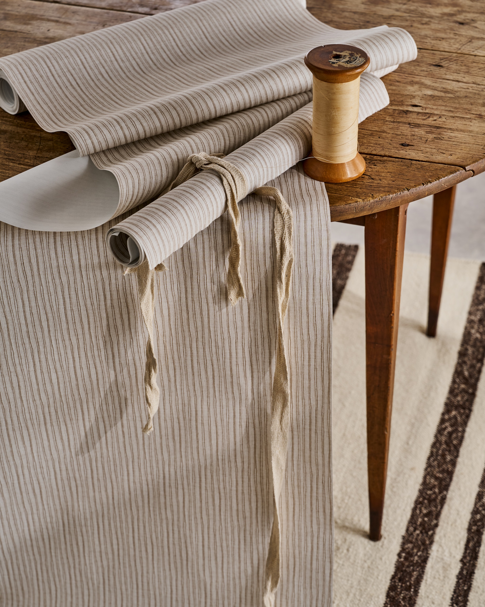 vtwonen behang Double Stripes, vliesbehangpapier, warm grey, 10 m x 53 cm (lxb), per rol € 35,99.> M.m.v. prinsheerlijkantiek.nl (tafel). vtwonen Landelijk 06-2026 | styling Cleo Scheulderman | fotografie Jeroen van der Spek