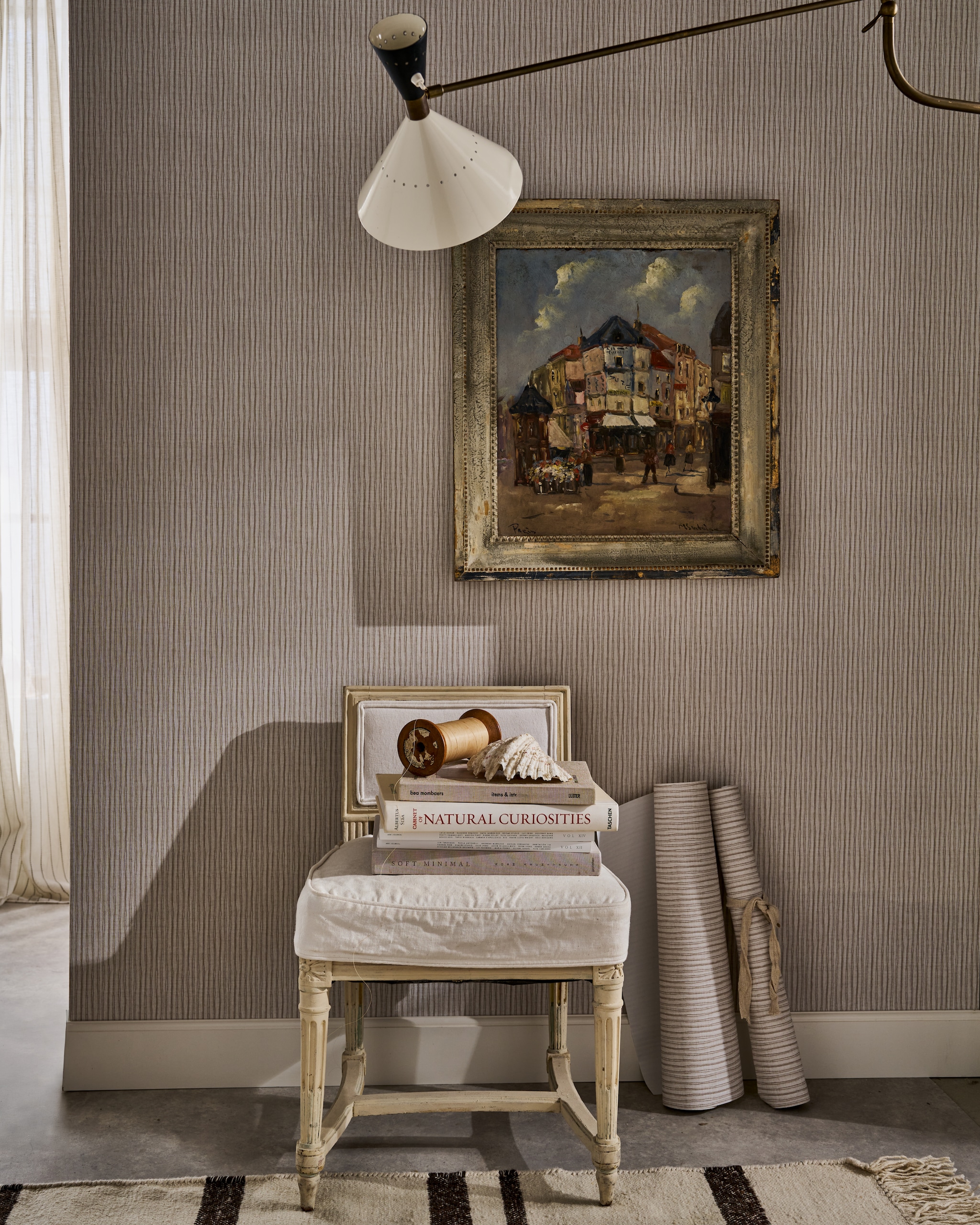 vtwonen behang Double Stripes, vliesbehangpapier, warm grey, 10 m x 53 cm (lxb), per rol € 35,99.^ M.m.v. prinsheerlijkantiek.nl (stoel, schilderij), hkliving.com (vloerkleed), pietjonker.nl (wandlamp). vtwonen Landelijk 06-2026 | styling Cleo Scheulderman | fotografie Jeroen van der Spek