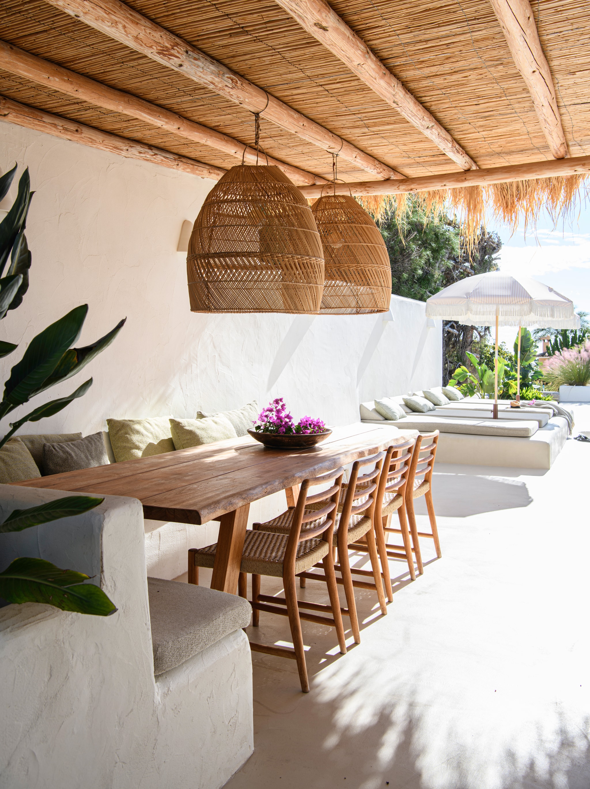Vloer gepolijst beton. Bank en ligbedden maatwerk, geverfd met kalkverf Chalk van Bauwerk Colour. Stoelen Vical Home. Hanglampen Cinq Étoiles. Parasol HKliving. Kussens maatwerk. vtwonen 08-2026 | styling Inge van Lieshout | fotografie Louis Lemaire | productie Insidehomepage