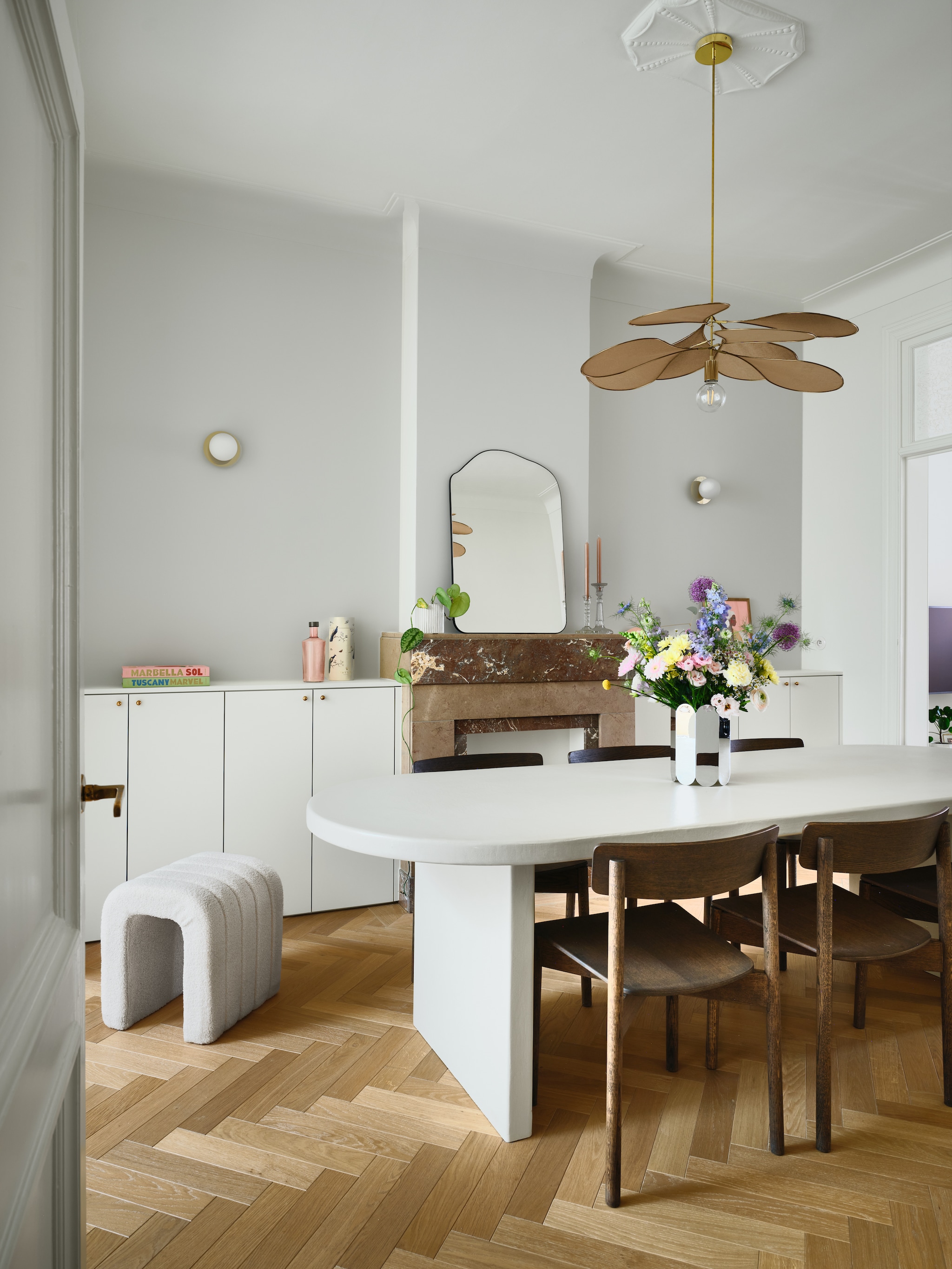 Wandkasten maatwerk naar eigen ontwerp. Messing greepjes op kasten en messing deurklinken Dauby. Poef Kwantum. Tafel maatwerk naar eigen ontwerp, afgewerkt met microtopping van B.a.i.t. Stoelen Takt. Hanglamp Georges via Couleur Locale. Wandlampen H&m Home. Vaas spiegelglas Muller Van Severen voor Hay. Spiegel Zara Home. Kandelaars vintage. Interieurboeken Assouline. Waterfles Paveau. Eiken visgraat parket Avance in Valetta via Hout Luyten. vtwonen 07-2026 | fotografie Mr. Frank