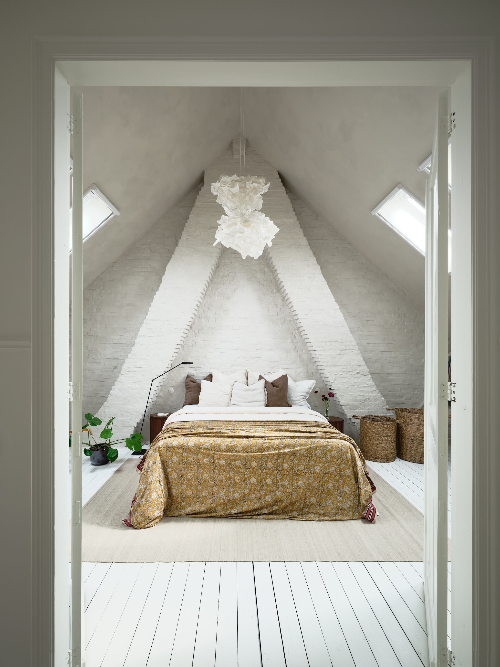 Verf muren en plafond Damico Dune van By Anouk. Hanglampen Ikea. Vloerlamp en vloerkleed Zara Home. Nachtkastjes H&m Home. Bloempot Serax. Bedsprei Doing Goods. Manden online vondsten. Originele plankenvloer, geschilderd in Ral 9010. vtwonen 07-2026 | fotografie Mr. Frank