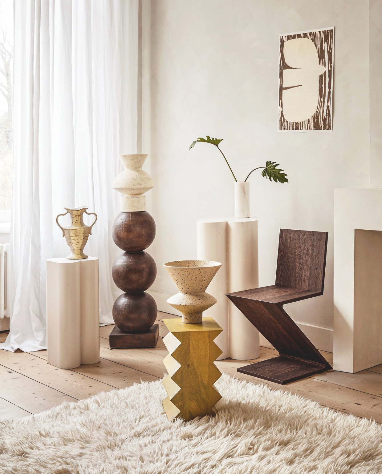 Zuiver plantenstandaards Shape, metaal, gebroken wit, 36x35x80 cm en 26x25x60,5 cm (bxdxh), set van 2 € 625,-, Urban Nature Culture bijzettafel Seba, zigzagrand, mangohout, groen, 30x23x40 cm (bxdxh) € 269,99, sokkel Bulb, mahoniehout, bruin, 28x83 cm (Øxh) € 299,-, vaas Thandi, keramiek, oranje € 79,99, vaas Thabo, keramiek, crème € 89,99, (shop.vtwonen.nl). Sukha poster, papier € 22,95 (sukha.nl). HKliving vaas met oren New Classics, steen, beige € 44,95 (hkliving.com). Cassina eetkamerstoel Zigzag, kersenhout, 37x43x74 cm (bxdxh) € 2095,- (rietveldoriginals.com).Benuta tapijt Baadal, wol, crème, 300x200 cm (lxb) € 799,- (benuta.nl). vtwonen 05-2026 | styling Marlies Does | fotografie Peggy Janssen