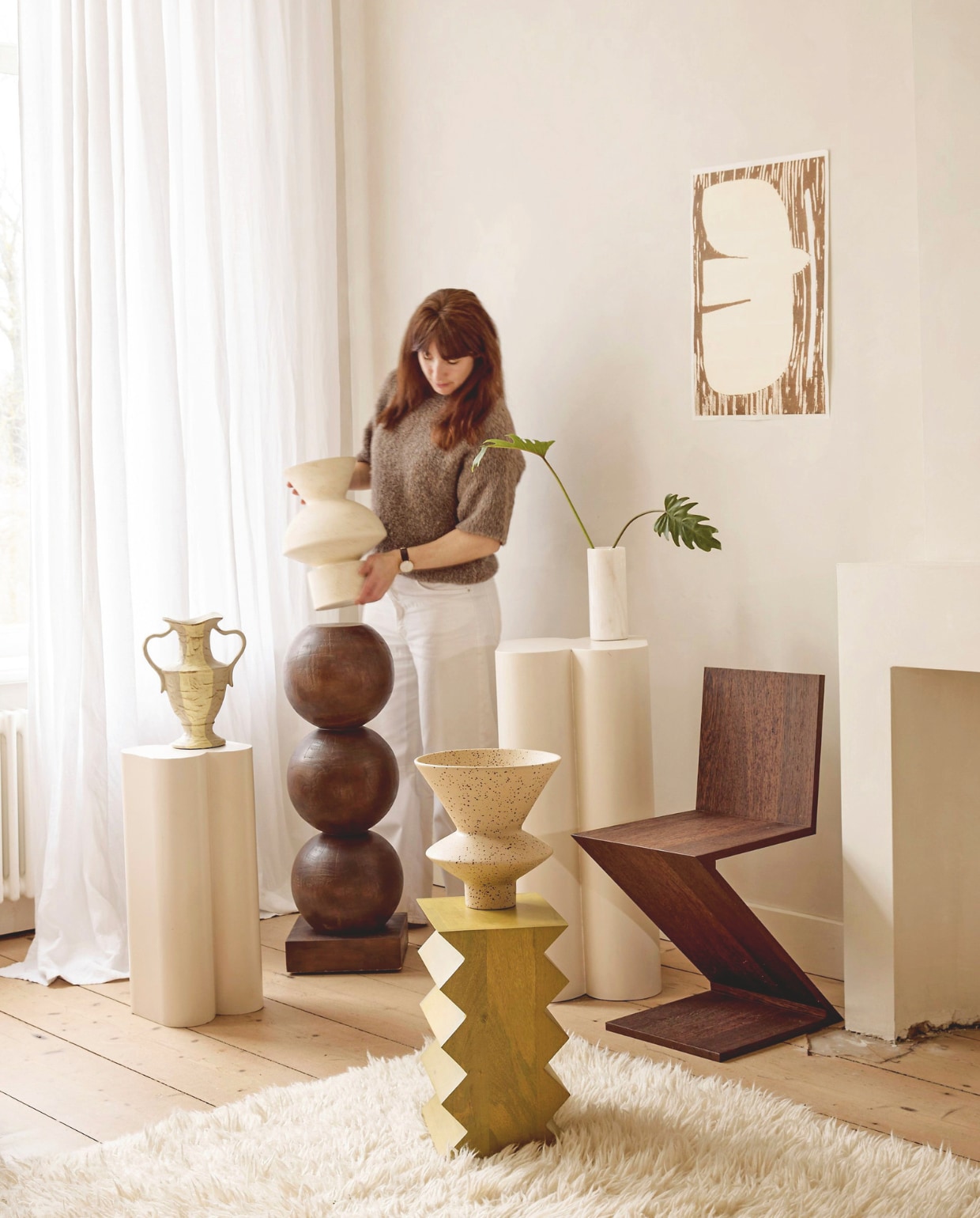 Zuiver plantenstandaards Shape, metaal, gebroken wit, 36x35x80 cm en 26x25x60,5 cm (bxdxh), set van 2 € 625,-, Urban Nature Culture bijzettafel Seba, zigzagrand, mangohout, groen, 30x23x40 cm (bxdxh) € 269,99, sokkel Bulb, mahoniehout, bruin, 28x83 cm (Øxh) € 299,-, vaas Thandi, keramiek, oranje € 79,99, vaas Thabo, keramiek, crème € 89,99, (shop.vtwonen.nl). Sukha poster, papier € 22,95 (sukha.nl). HKliving vaas met oren New Classics, steen, beige € 44,95 (hkliving.com). Cassina eetkamerstoel Zigzag, kersenhout, 37x43x74 cm (bxdxh) € 2095,- (rietveldoriginals.com).Benuta tapijt Baadal, wol, crème, 300x200 cm (lxb) € 799,- (benuta.nl). vtwonen 05-2026 | styling Marlies Does | fotografie Peggy Janssen