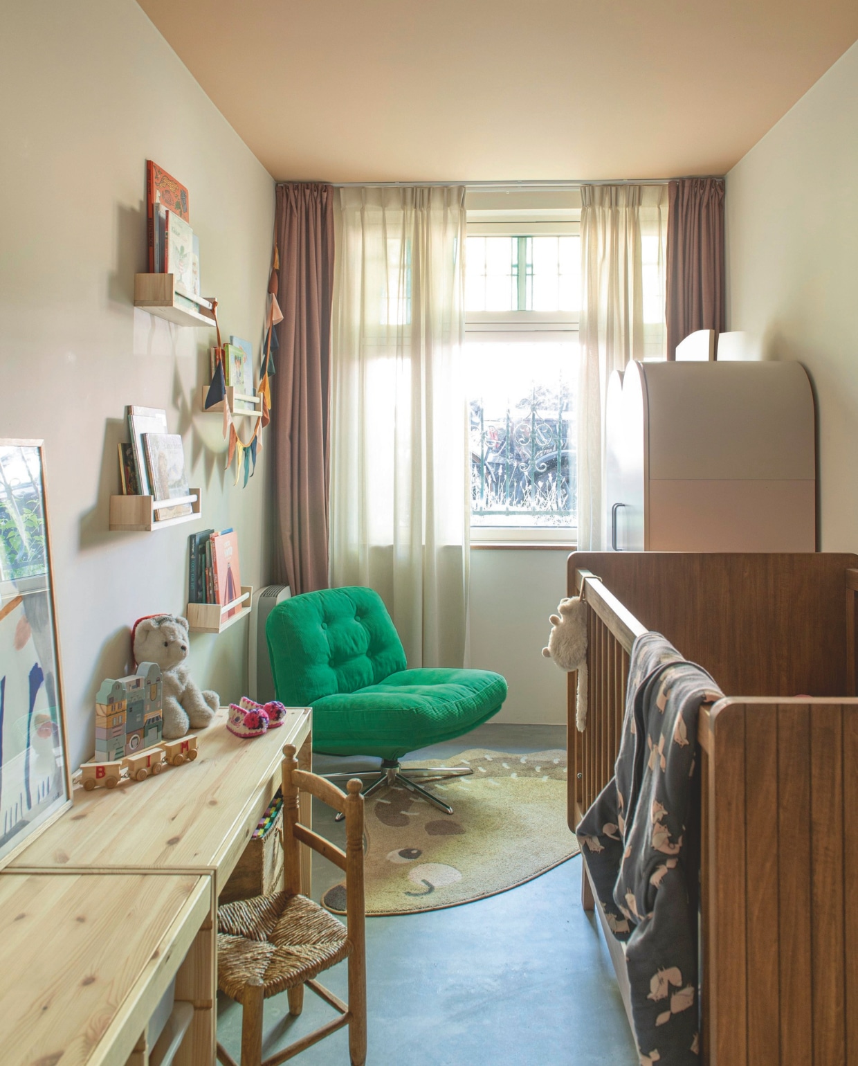 Vloer microcement. Muurverf Dimity en plafondverf Setting Plaster van Farrow & Ball. Gordijnen Kwantum. Ledikant Bopita. Kast Jotex. Houten kinderstoel tweedehands. Poster The Poster Club. Kinderbureau, fauteuil, wandrekken en vloerkleed Ikea. vtwonen 05-2026 | fotografie Caroline Coehorst