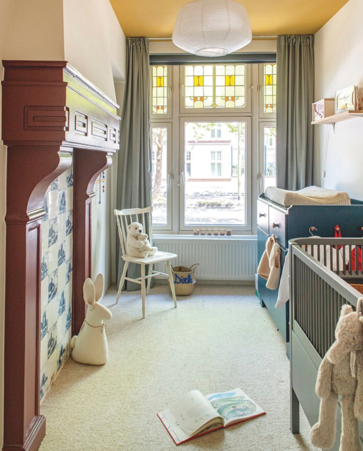 Vloer Carpetright. Muurverf Dimity, plafondverf India Yellow en schouwverf Preference Red van Farrow & Ball. Tegels in schouw origineel. Gordijnen Ikea. Stoel en commode tweedehands. Ledikant Sebra. Merantihouten wandplank zelfgemaakt. vtwonen 05-2026 | fotografie Caroline Coehorst