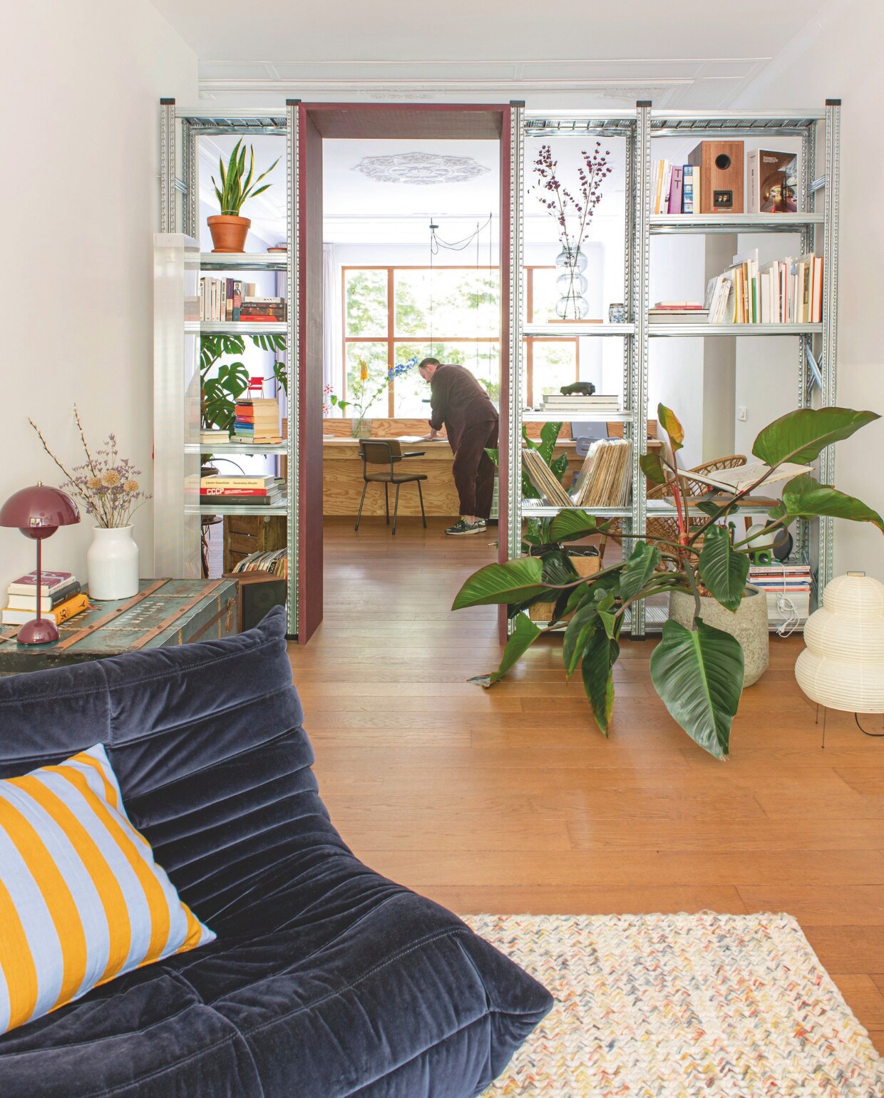 Eikenhouten vloer origineel. Stellingkast De Stelling Amsterdam. Fauteuil Ligne Roset. Sierkussen A World Of Craft. Papieren lamp Vitra. Tafellamp &Tradition. Bureau gemaakt van Pools grenen door Warns Woodworks. Stoel kringloop. vtwonen 05-2026 | fotografie Caroline Coehorst