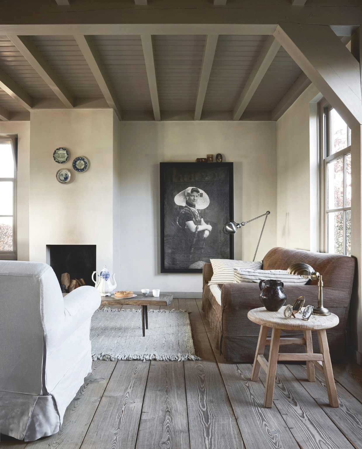 Zuiver vloerkleed Frills, wol, beige, 240x170 cm (lxb) € 469,-, vtwonen sierkussen, katoen en linnen, beige € 44,95 (shop.vtwonen.nl). More Than Canvas oud gemaakt canvasdoek, zwart en wit, 100x150 cm (bxh) € 159,- (morethancanvas.nl). Sijmen Interieur baklijst, mdf, zwart, 110x160 cm (bxh) € 325,- (sijmen-interieur.nl). Het Kabinet Wonen salontafel, oud hout en metaal, naturel, 203x43x36,5 cm (bxdxh) € 1595,-, bijzettafel Peking, hout, naturel, 50x50 cm (bxh) € 295,- (hetkabinet.nl). Jieldé vloerlamp, staal, zilverkleurig, 33x33x180 cm (bxdxh) € 750,- (newindustrials.com). Weldaad tafellamp, metaal en messing, brons € 155,- (weldaad.com). Antieke lijsten op bijzettafel, zilver, vanaf € 85,-, antieke lijsten op baklijst, zilver, vanaf € 85,-, oude borden met spreuken, vanaf € 15,- (kramer.amsterdam). Tableware Amsterdam koffiepot xl, porselein, wit en blauw € 45,- (tableware.amsterdam). Overig privébezit.