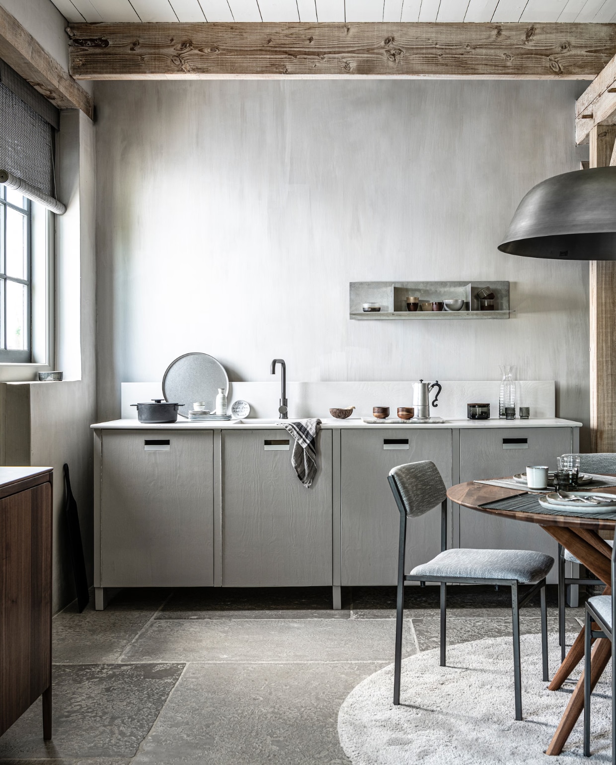 Op de wanden kalkverf Warm Grey van Pure & Original 1 liter € 40,75 (pure-original.nl).Keuken op maat gemaakt, prijs op aanvraag (com-anders.nl). Kraan gun metal € 169,- (tworooms.nl). Zwarte pan Surface van Serax € 126,-, glas Ripple van Ferm Living, set van 4 € 35,-, zwarte serveerplank Acacia van Bloomingville 70 cm € 60,99, houten theekop Collage van Serax, per stuk € 12,80 (vtwonen.nl). Percolator Lady Anne € 59,-, tweekleurige keramieken mok Earth € 17,50, stonewashed rond stalen dienblad € 69,- (bymolle.com). Sake set € 39,75 (japansewinkeltje.nl). Bordje met geschreven tekst van Anouk Kramer € 30,- (archive-store.nl). Glazen opbergpot met houten deksel € 19,95, glazen karaf € 24,95 (nordal.eu). Wandplank Rivet, small, onbehandeld aluminium 87,6×24,4×20,6 cm (lxdxh) € 615,- (framacph.com). Hanglamp Cloche Three, geborsteld aluminium, 81×25 cm (Øxh) € 750,- (vanduivenboden.nl). Vintage design stoelen met nieuwe stoffering € 850,-, walnoothouten eettafel Lakri 120 cm (Ø) € 2984,- (goeds.nl). Gehamerd bestek, per stuk € 5,99, bamboe placemat, set van 2 € 6,99 (zarahome.com). Ronde borden van HK Living vanaf € 11,95, rechthoekige borden van Serax vanaf € 11,95, mok van HK Living € 6,95, schaal € 10,95 (loftloft.nl). Walnoothouten dressoir Rikke € 2960,- (demachinekamer.nl). Rond grijs vloerkleed € 3034,- (homestede.nl). Roll-up gordijn bamboo flat sticks prijs op aanvraag (nature-deco.com).
 vtwonen 11-2021 | styling Kim van Rossenberg | fotografie Sjoerd Eickmans | assistentie Sanne van der Beek en Meike Linthorst