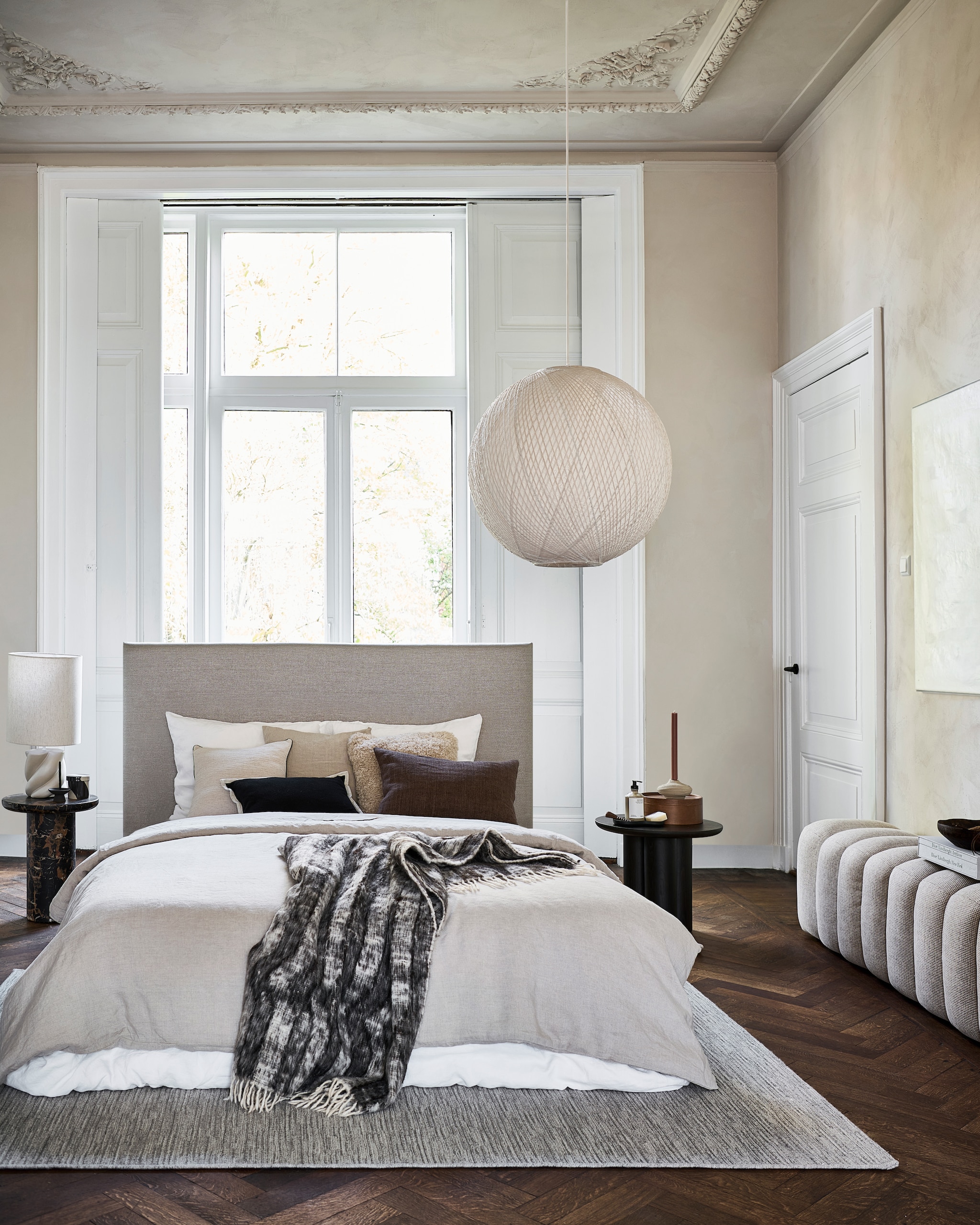 vtwonen vloerkleed Nature cord, wol, antraciet melé, 230x160 cm (lxb) € 449,-  M.m.v. polspotten.nl (faux marmeren bijzettafel), homecouturebybernie.com (bed met linnen hoofdbord), yumeko.nl (dekbedovertrek en kussenslopen), zarahome.com (kussens met bies, beige sprei), velv.nl (beige linnen kussen), studio-henk.nl (houten bijzettafel), loods5.nl (gestoffeerde bank), @ansdekruyf (schilderij). Overig privébezit. vtwonen 8-2026 | fotografie Sjoerd Eickmans | styling Danielle Verheul