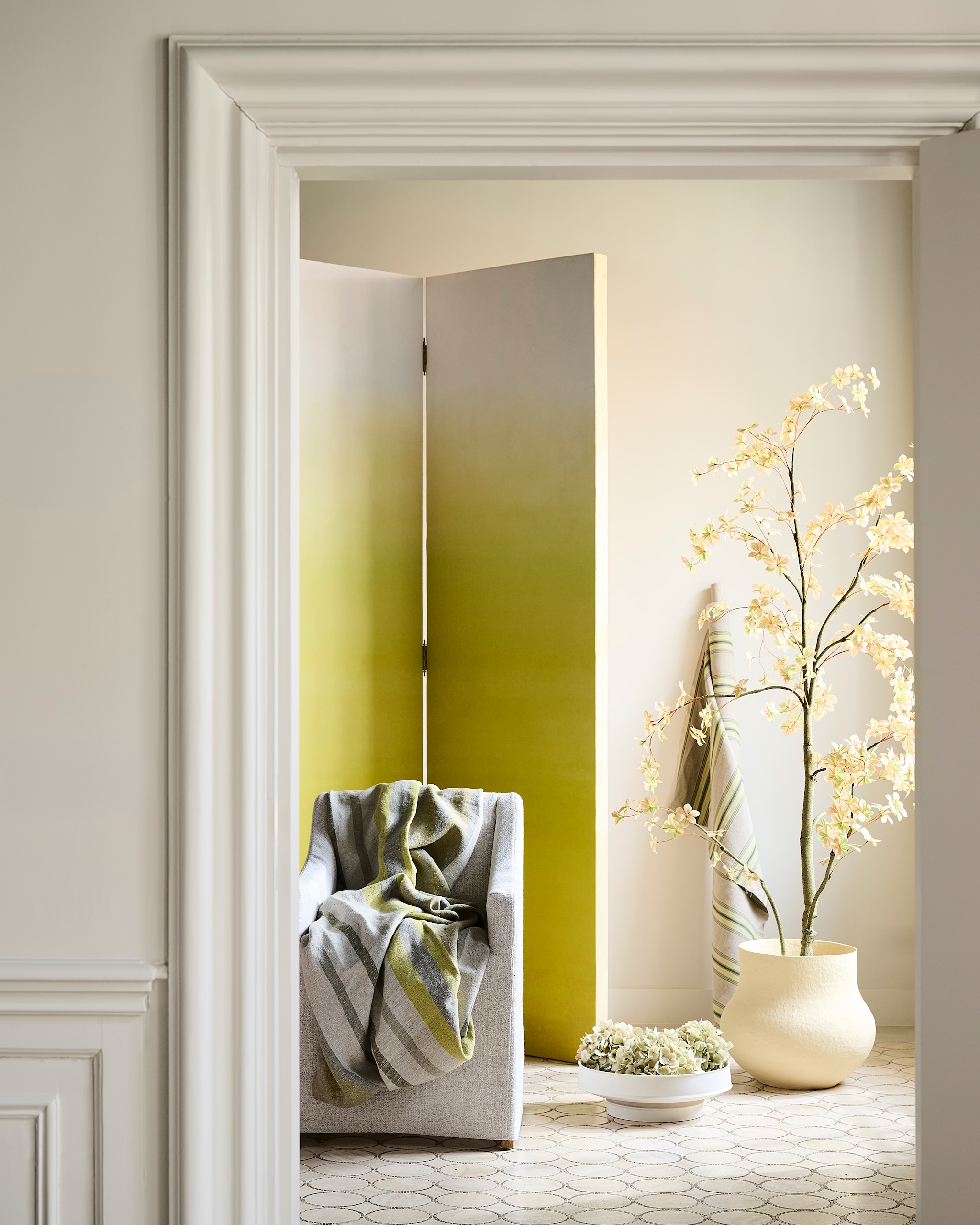 Designers Guild behang Shoshi, papier, lemongrass, 140x300 cm (bxh), per rol € 315,-, streepstof Brera Striato, linnen, groen, per meter € 146,-, tijkstreepstof Loire Lime, katoen, geel, per meter € 174,- (wva.nl). Farrow & Ball muurverf Skimming Stone, 2,5 liter € 119,- (farrow-ball.com). Combitex kamerscherm, hout, prijs op aanvraag (com-anders.nl). Rivièra Maison eetkamerstoel Firenze, linnen, naturel, 61x56x85,5 cm (bxdxh) € 499,- (rivieramaison.com). Urban Nature Culture pot Frieda, papier-maché, zachtgeel € 219,99 (shop.vtwonen.nl). Serax schaal Dune by Kelly Wearstler, keramiek, wit € 151,- (serax.com). vtwonen Landelijk 07-2026 | Styling Marianne Luning | Fotografie Sjoerd Eickmans