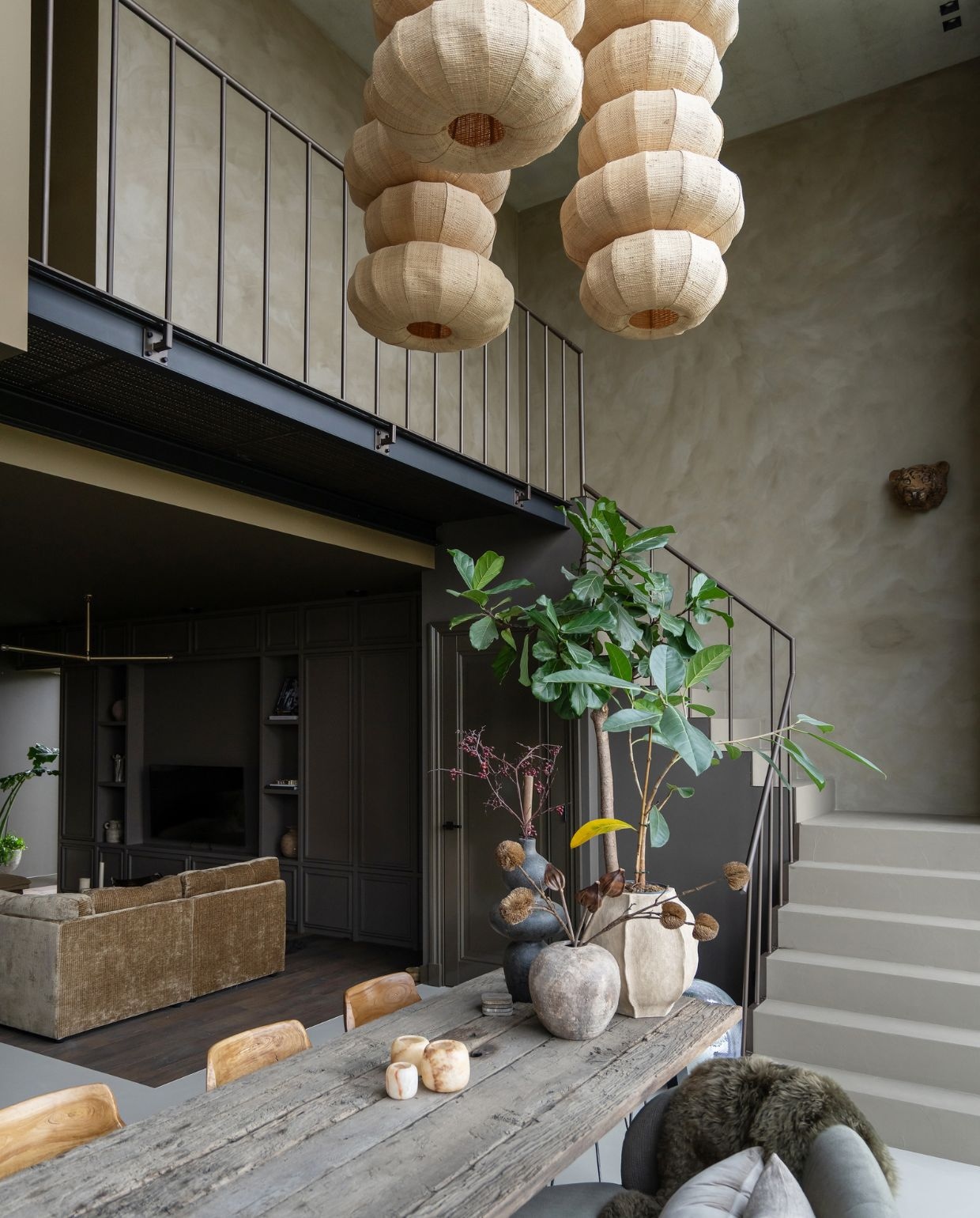 Jet combineerde meerdere lampen, vergelijkbaar met Zosia van Light & Living, tot deze hanglampen. Bank Spektakel Wonen. Soortgelijk: vaas rechts model L van Ernst, waxinelichthouders Solulu. Op de trap beton ciré 940 Honey van Betonstunter. Wand boven trap kalkverf Mud Soldier van Lab colour the world. Wand onder trap Sand Storm van Pure & Original. Wandkast woonkamer Soho van Lab colour the world. Plafond zithoek F4.16.22 van Sikkens. vtwonen 05-2026 | styling Jet Hendriks | fotografie Lotte van Uittert