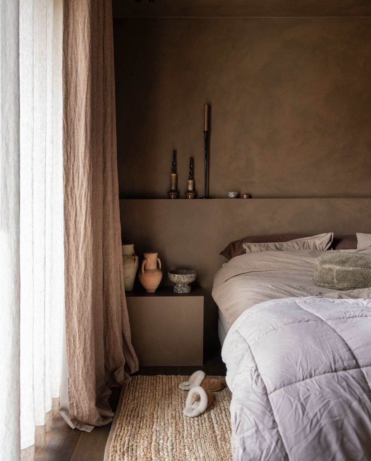 Gordijnen Heijligers Roelofs Wonen. Vazen op nachtkastje kringloopwinkel. Beddengoed Suite 702. Sloffen Ugg. Wand geverfd in kalkverf Charcoal van Lab colour the world. vtwonen 05-2026 | styling Jet Hendriks | fotografie Lotte van Uittert