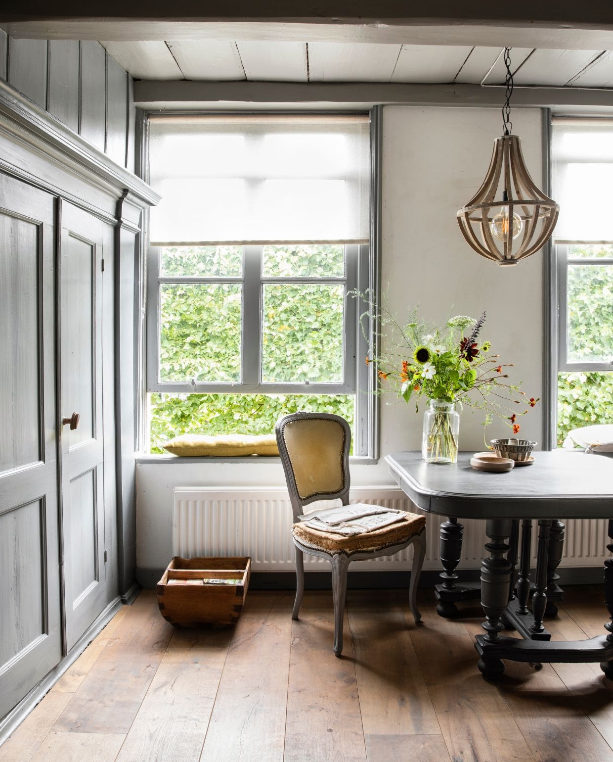 Hanglamp Het Kabinet. Oude tafel geschilderd in mat grijs. De klassieke stoel werd wat ruiger zonder bekleding. Bloemen uit eigen tuin. Houten bak brocante. Vloer Woonboerderij Maja. Kleur houtwerk Ral 7023.