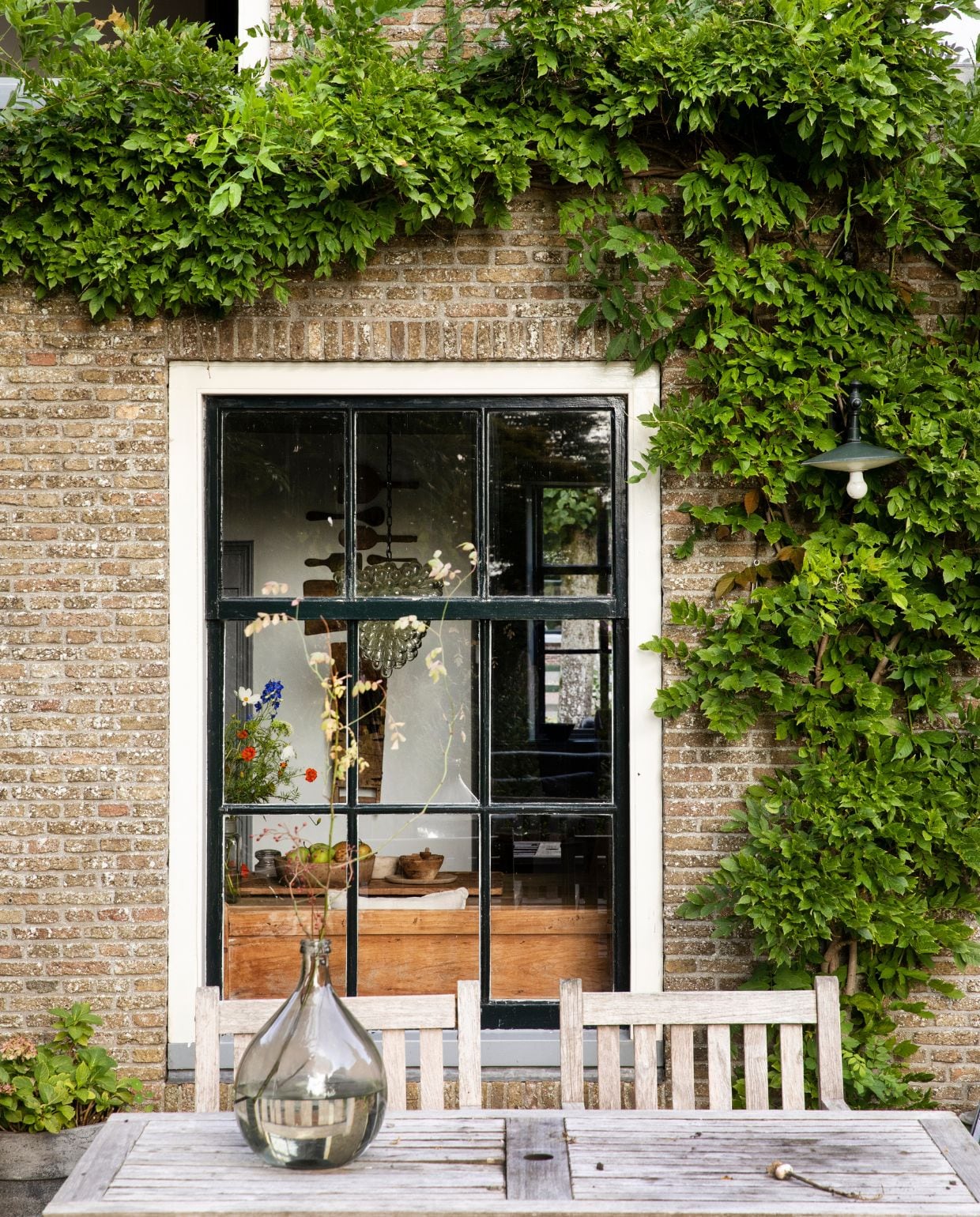 Kijkje van het terras in de keuken door het ongebruikelijk grote raam voor een huis uit 1625. vtwonen Landelijk 05-2026 | styling Miriam Hannemann | fotografie André Reuter
