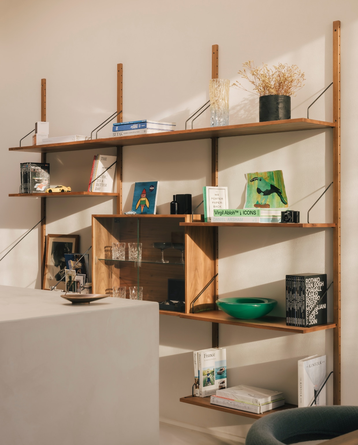 Het modulaire wandsysteem van Royal System vulde Nachtergaele met persoonlijke items, waaronder boeken en internationale magazines over kunst, design en reizen. De groene resin schaal is een ontwerp van Vincent de Rijk voor Rira Objects. Stijlvol Wonen 9-2025 | fotografie Katoo Peeters