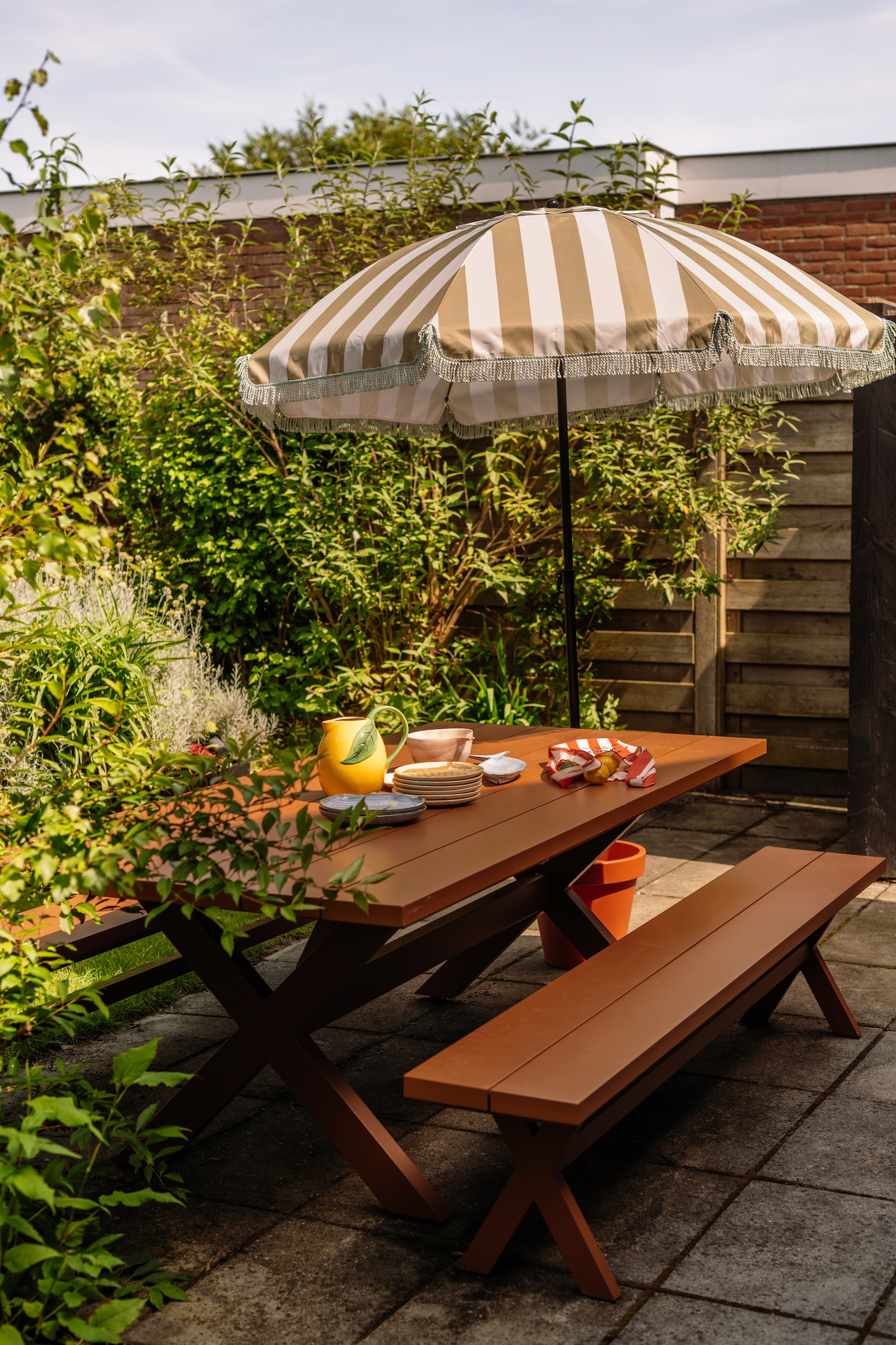 Picknicktafel Woood. Parasol en servies Mica Decorations. Parasolvoet zelf gemaakt met plantenpot. Gestreepte tas Sézane. vtwonen 07-2026 | fotografie Lotte van Uittert