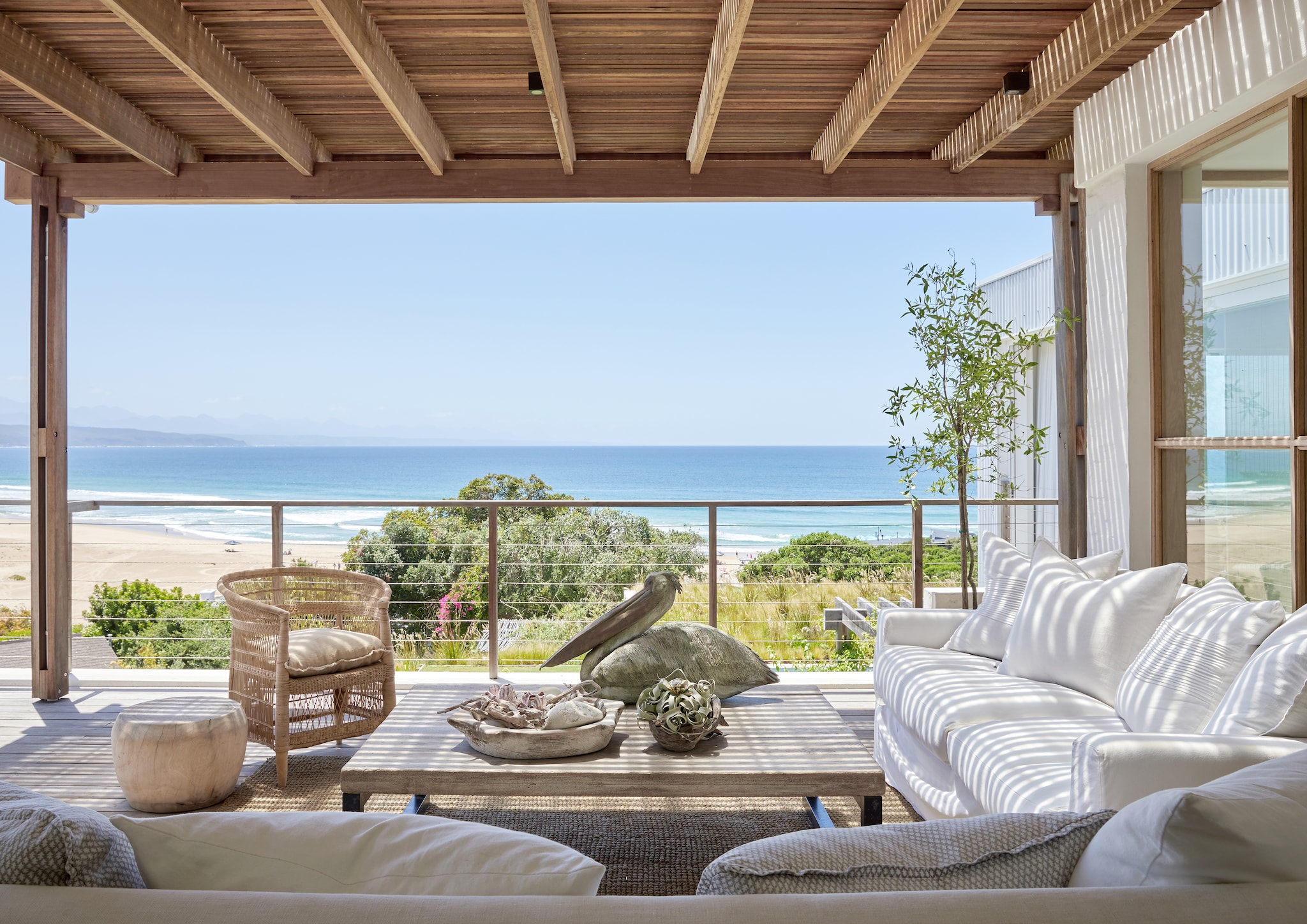 Uitzicht op de bergen, het strand en de rivierdelta: aan de plek mankeert niets. Gevlochten stoel Malawi Cane via Atelier Pomme. Bronzen pelikaan van beeldhouwer Italia Greig. Zitmeubels The Private House Company. vtwonen Landelijk 08-2026 | fotografie Greg Cox