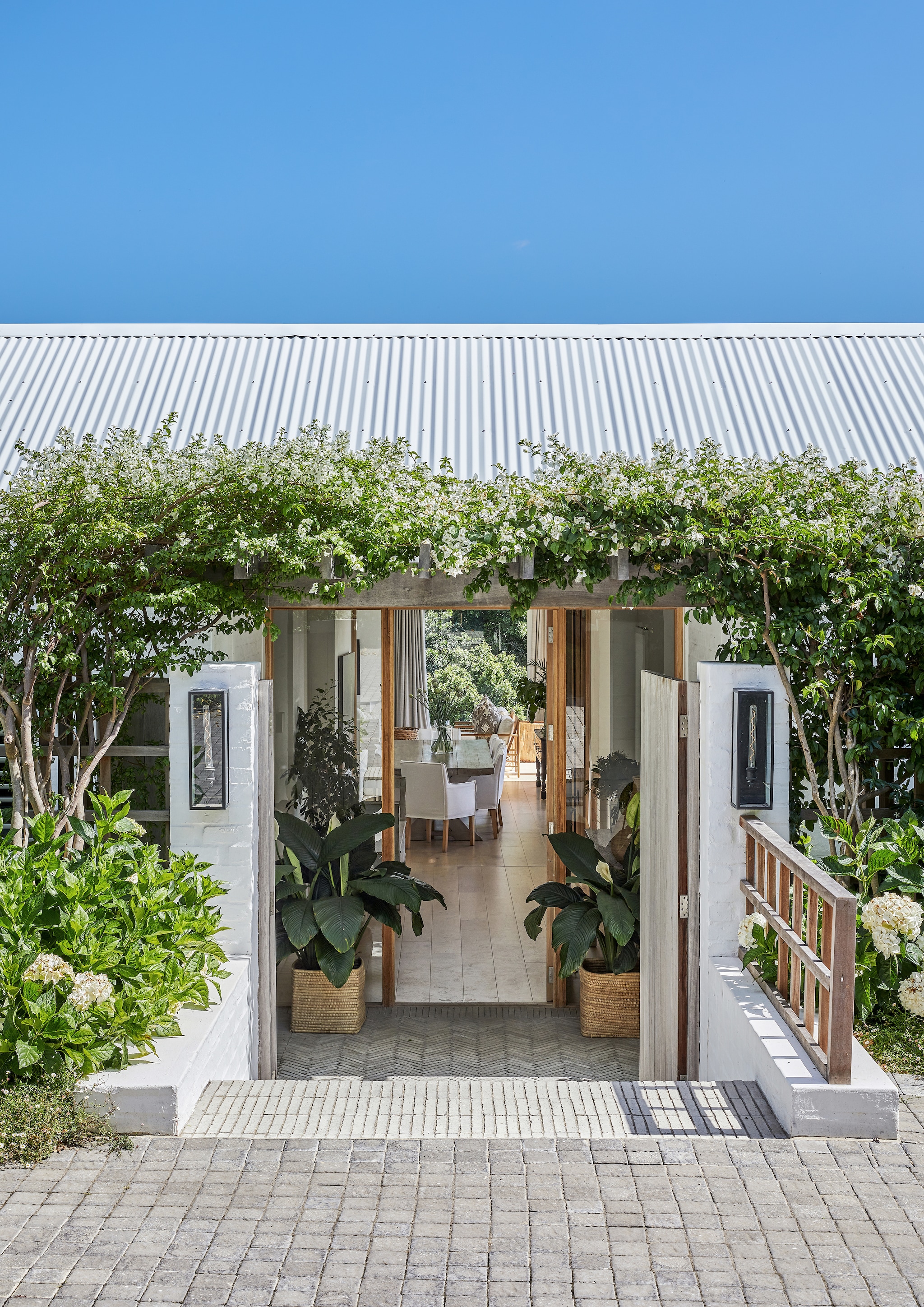 Het huis ligt in een heuvel ingebed. De entree bevindt zich aan de bovenzijde van helling. De pergola rond de entree is begroeid met heerlijk geurende jasmijn. vtwonen Landelijk 08-2026 | fotografie Greg Cox