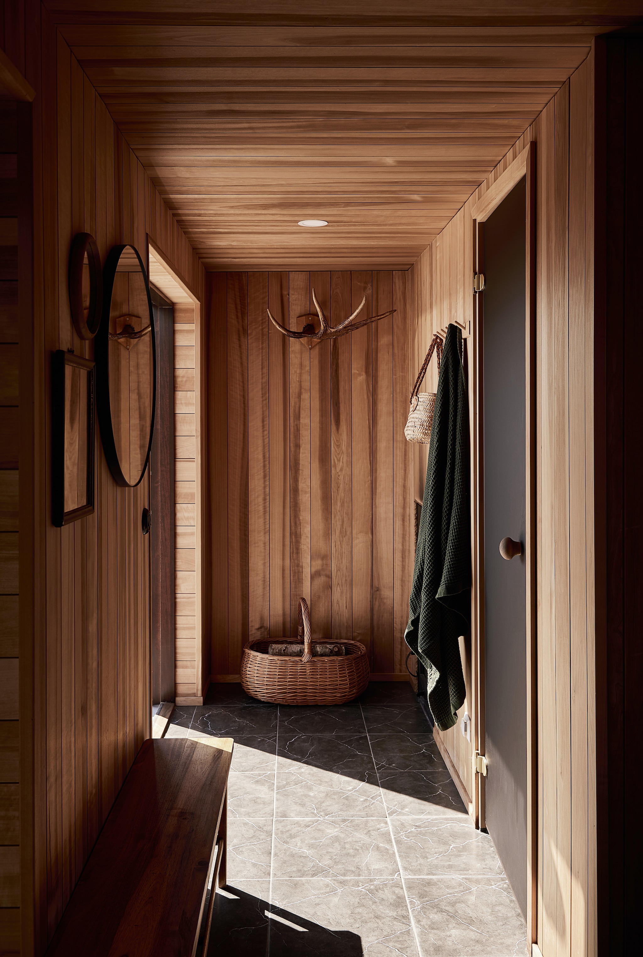Achter de glazen deur bevinden zich de sauna en de douche. Soortgelijke mand Aangeenbrug. Houten bankBaanwoods. vtwonen Landelijk 08-2026 | Fotografie Krista Keltanen | Productie Living Inside